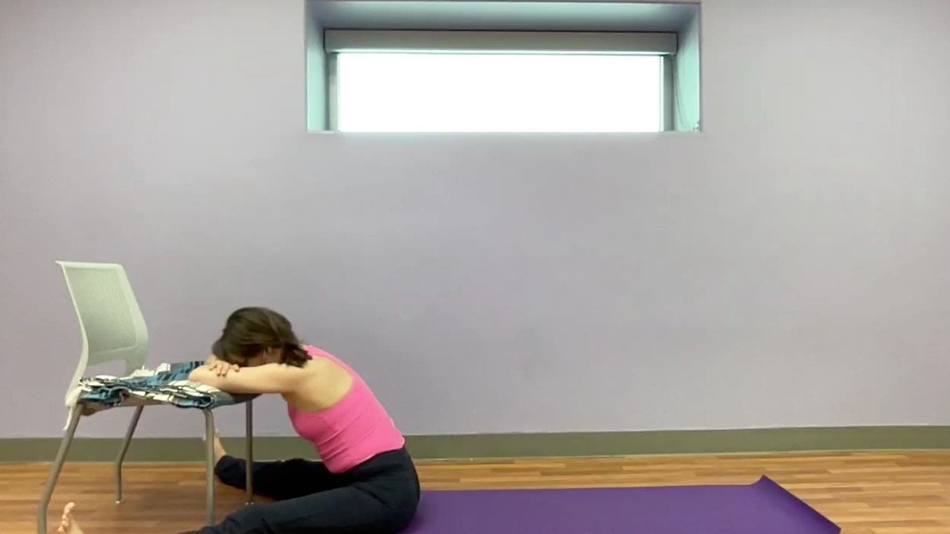 Image of yoga teacher practicing Wide-Angled Seated Forward Bend with elbows on chair.