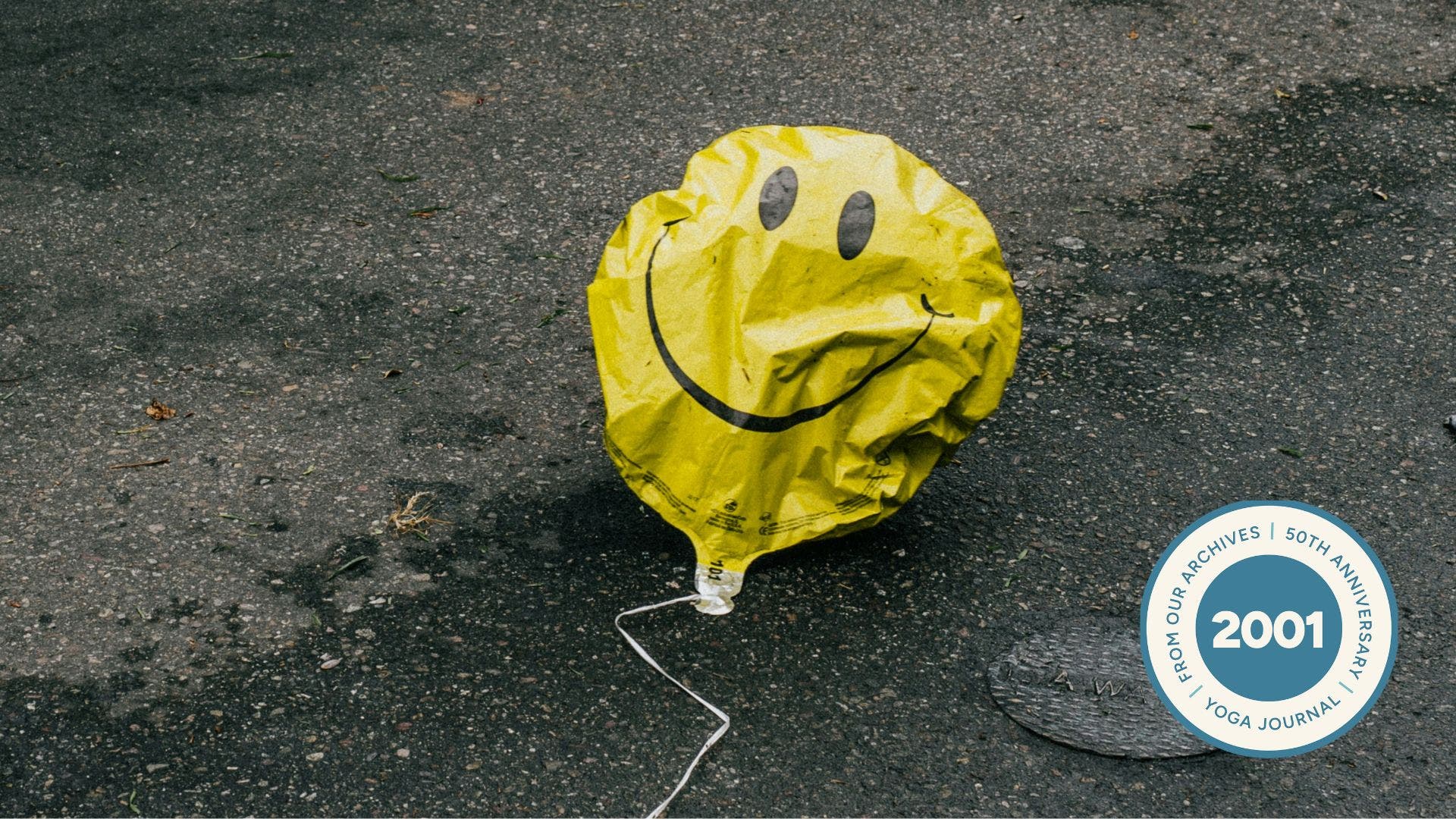 Image of a deflated smiley face balloon on the street.