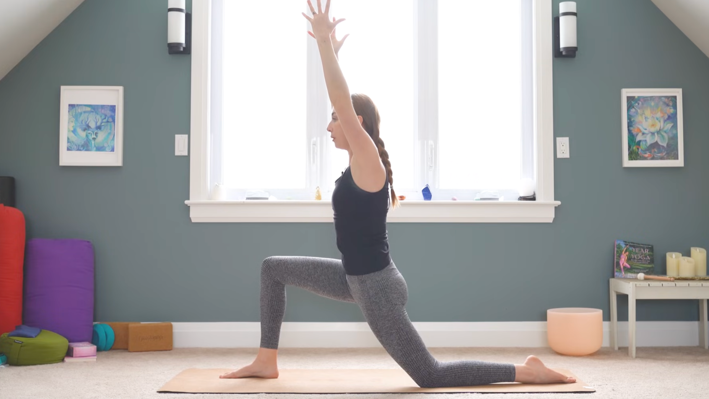 woman in low lunge pose on yoga mat with hands extended overhead during anterior pelvic tilt exercises
