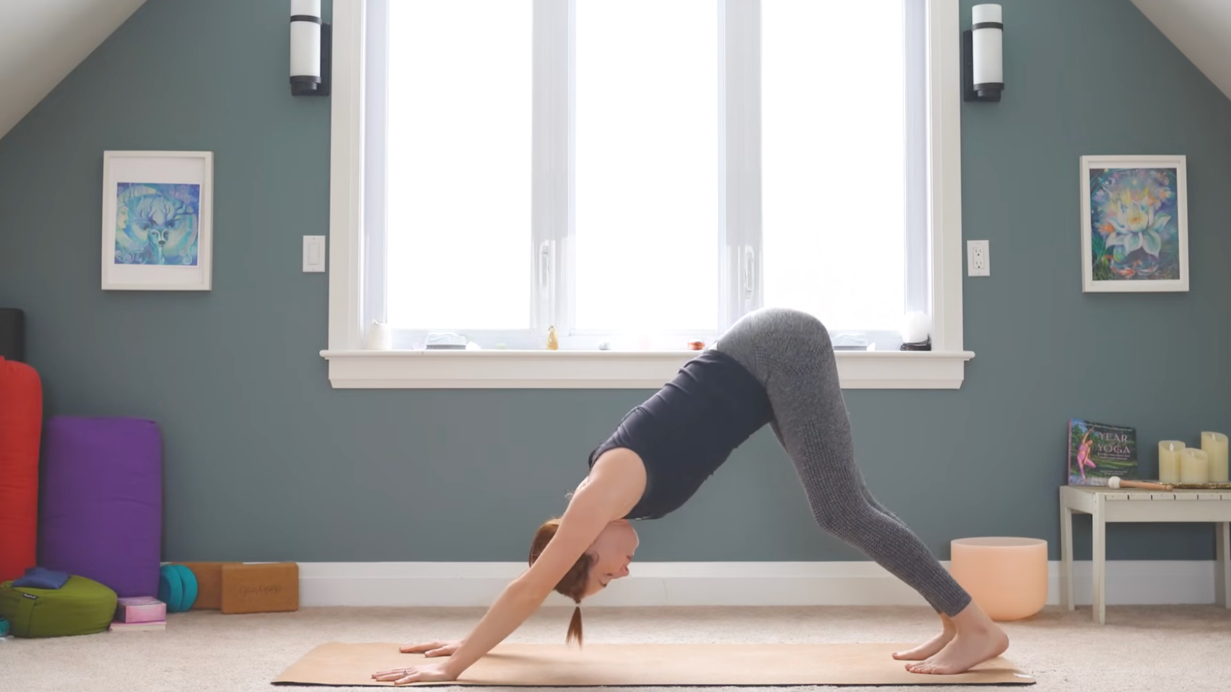 woman in downward facing dog pose on yoga mat in home