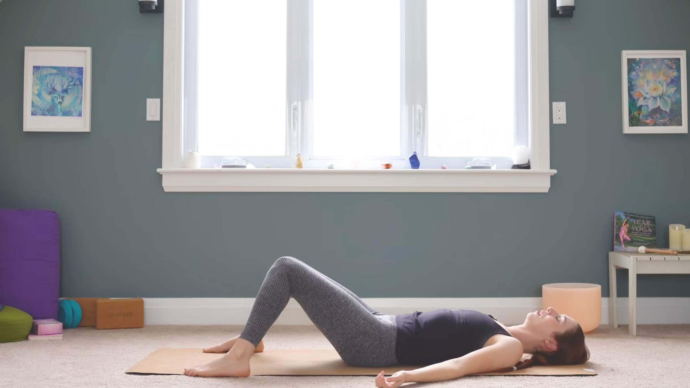 woman in reclined savasana but with feet on mat and knees bent