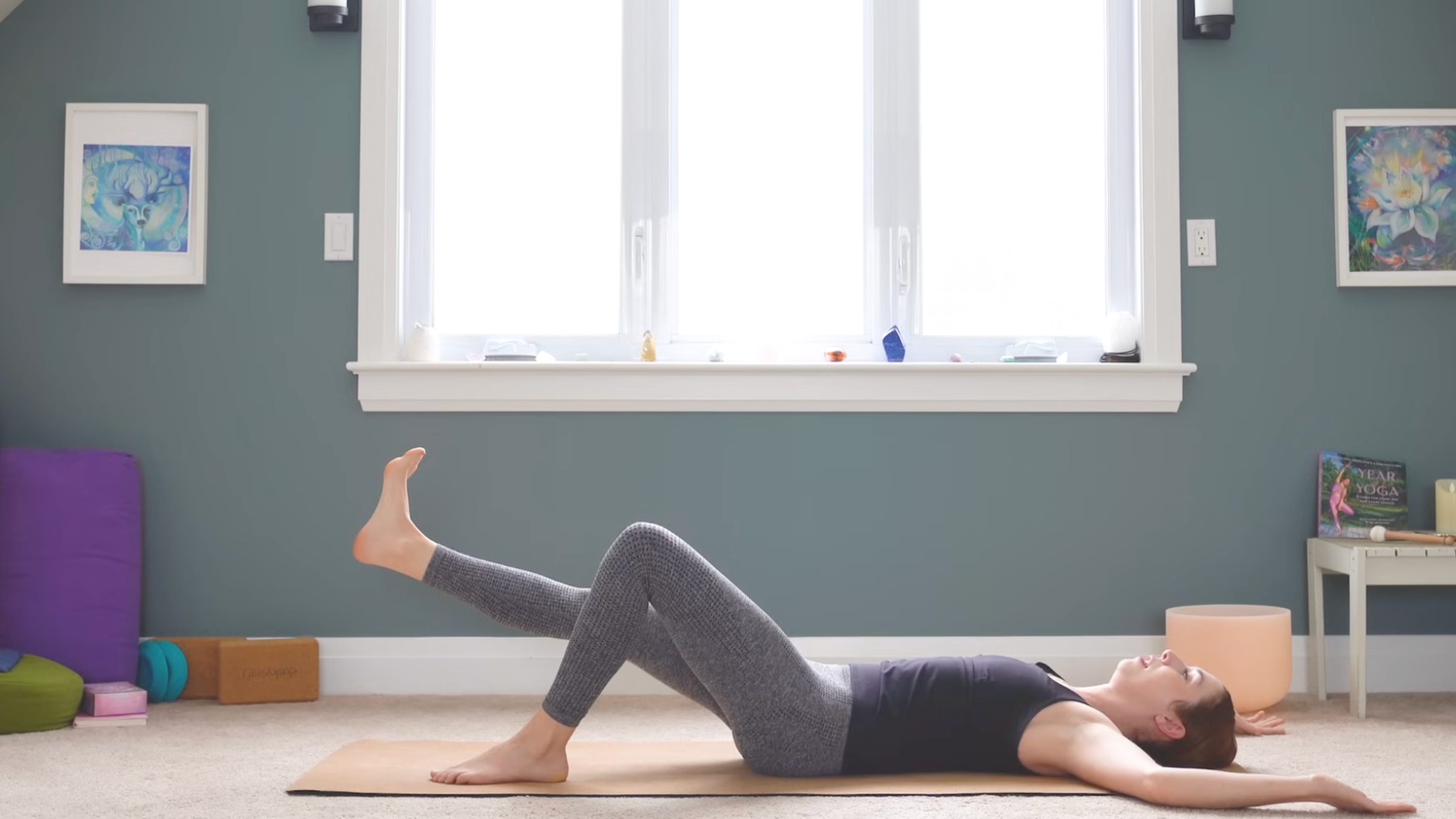 woman in reclined position on yoga mat on floor has left knee bent and left foot on mat while right leg is extended, foot flexed and lifted parallel to the ground during anterior pelvic tilt exercises