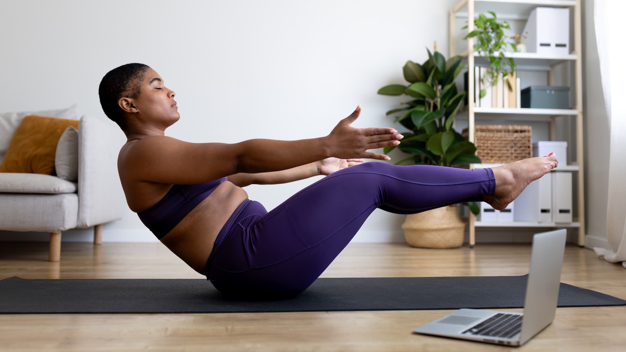 A woman in Boat Pose, part of her full-body strength workout