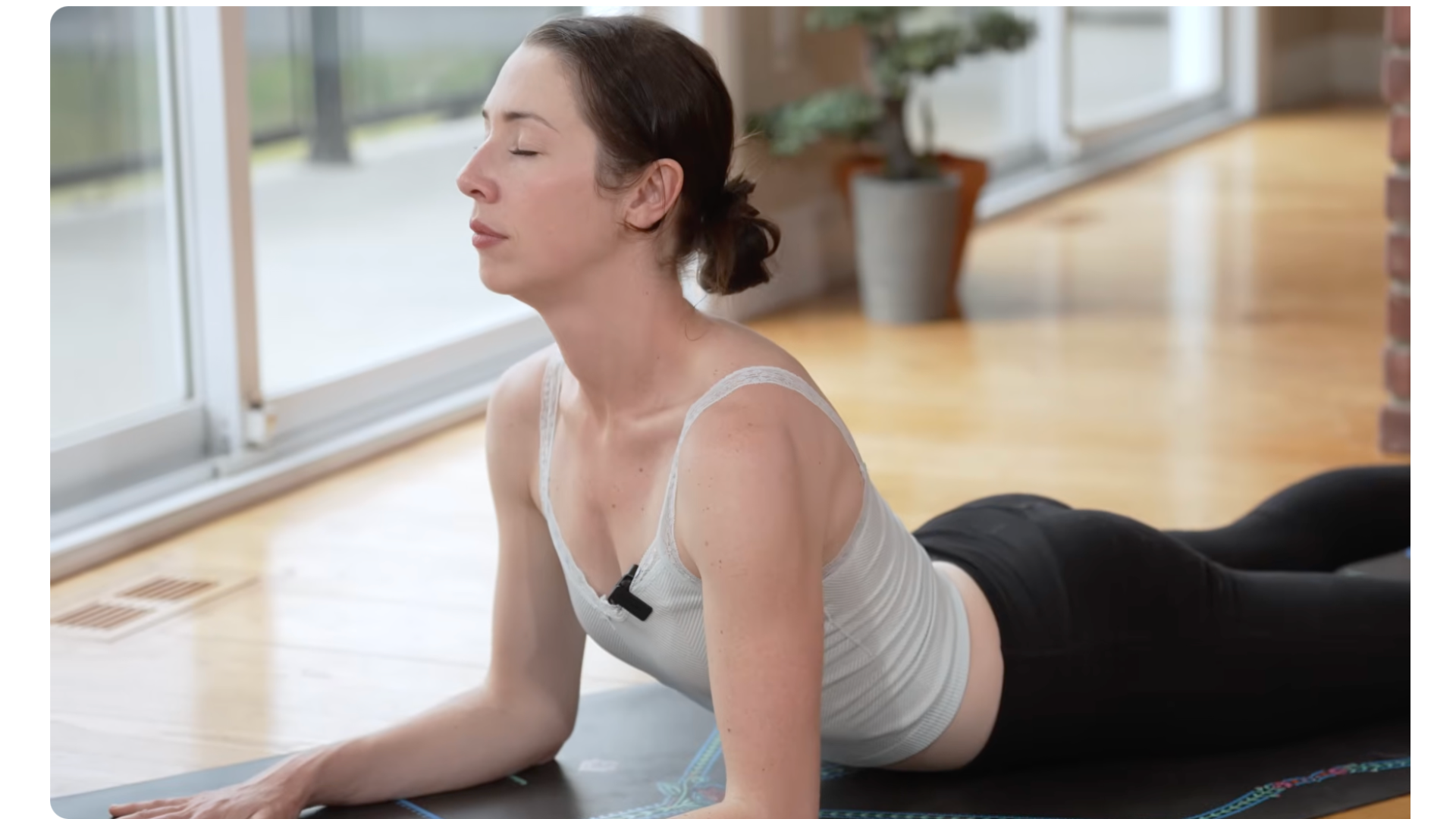 yoga teacher lying on a mat, belly down, with her forearms propping up her chest