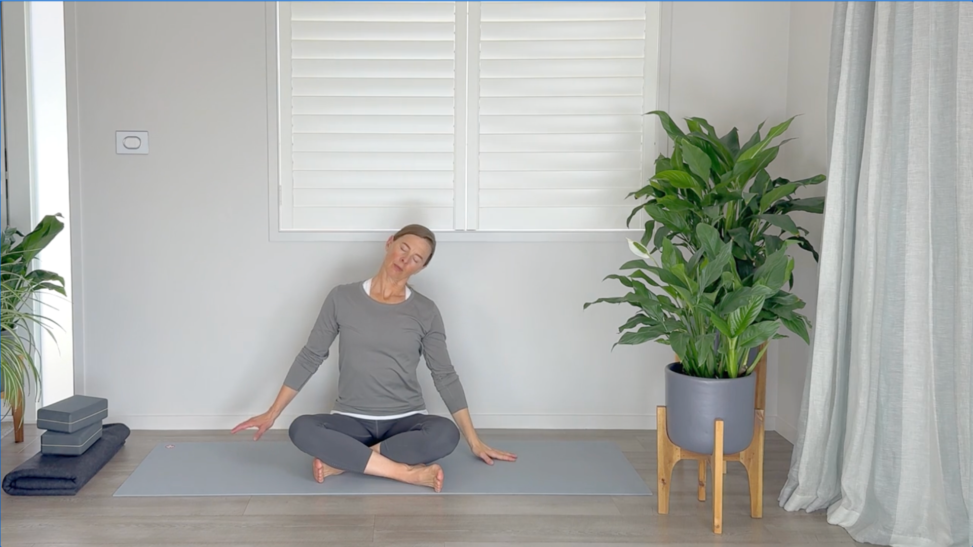 Woman sitting on a yoga mat leaning her head to one side