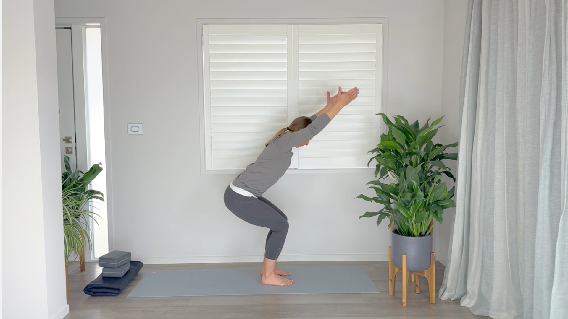Yoga teacher sitting back in Chair Pose to build strong glutes