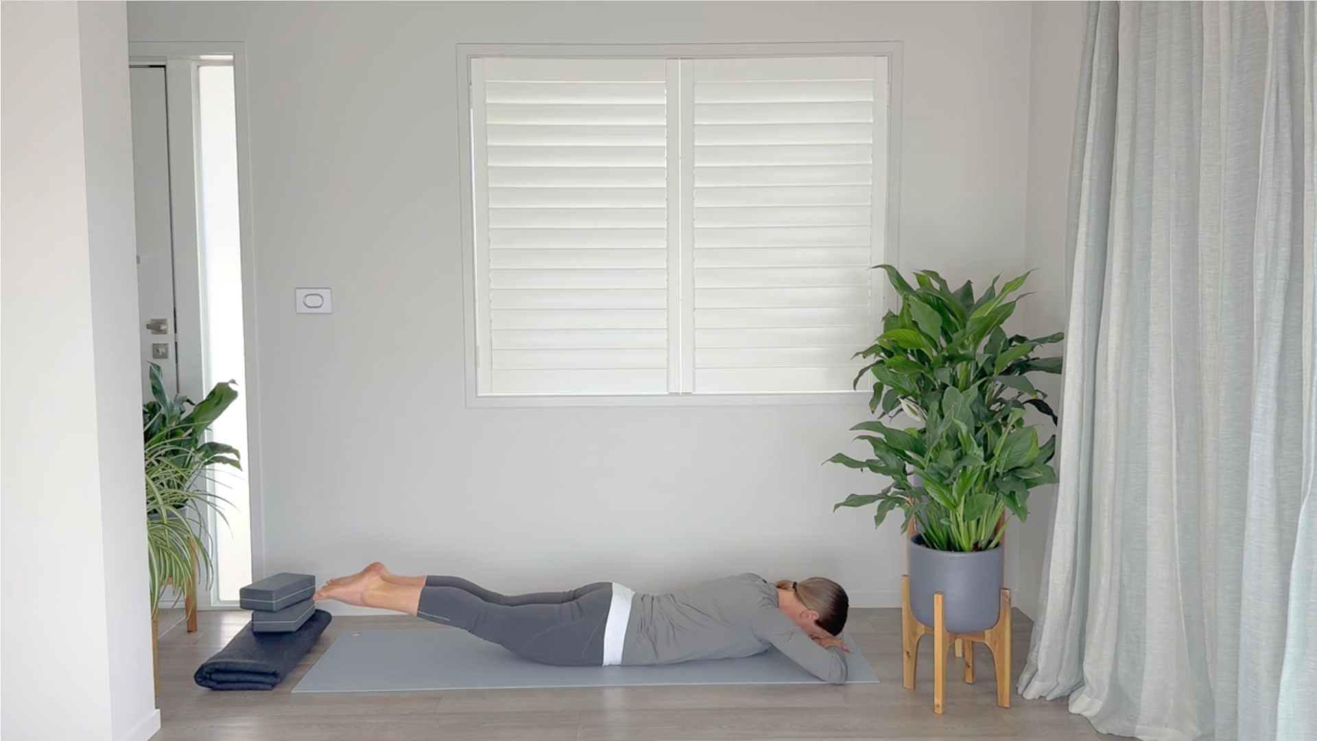 Yoga teacher lying belly down on a yoga mat and lifting her legs to build strong glutes