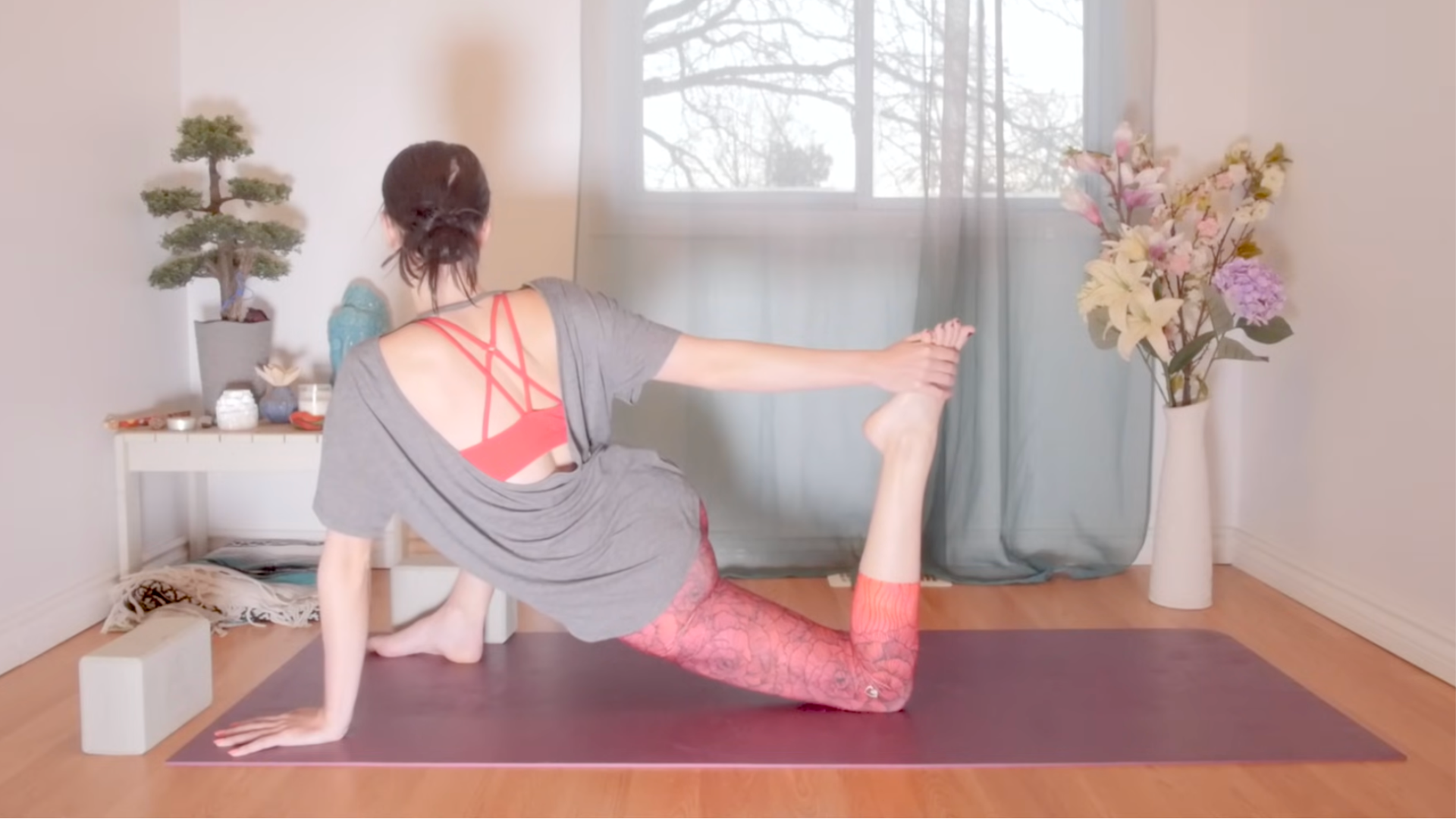 Woman in a quad stretch while practicing yoga for root chakra balancing