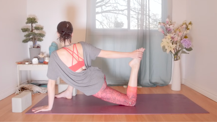 Woman in a quad stretch while practicing yoga for root chakra balancing