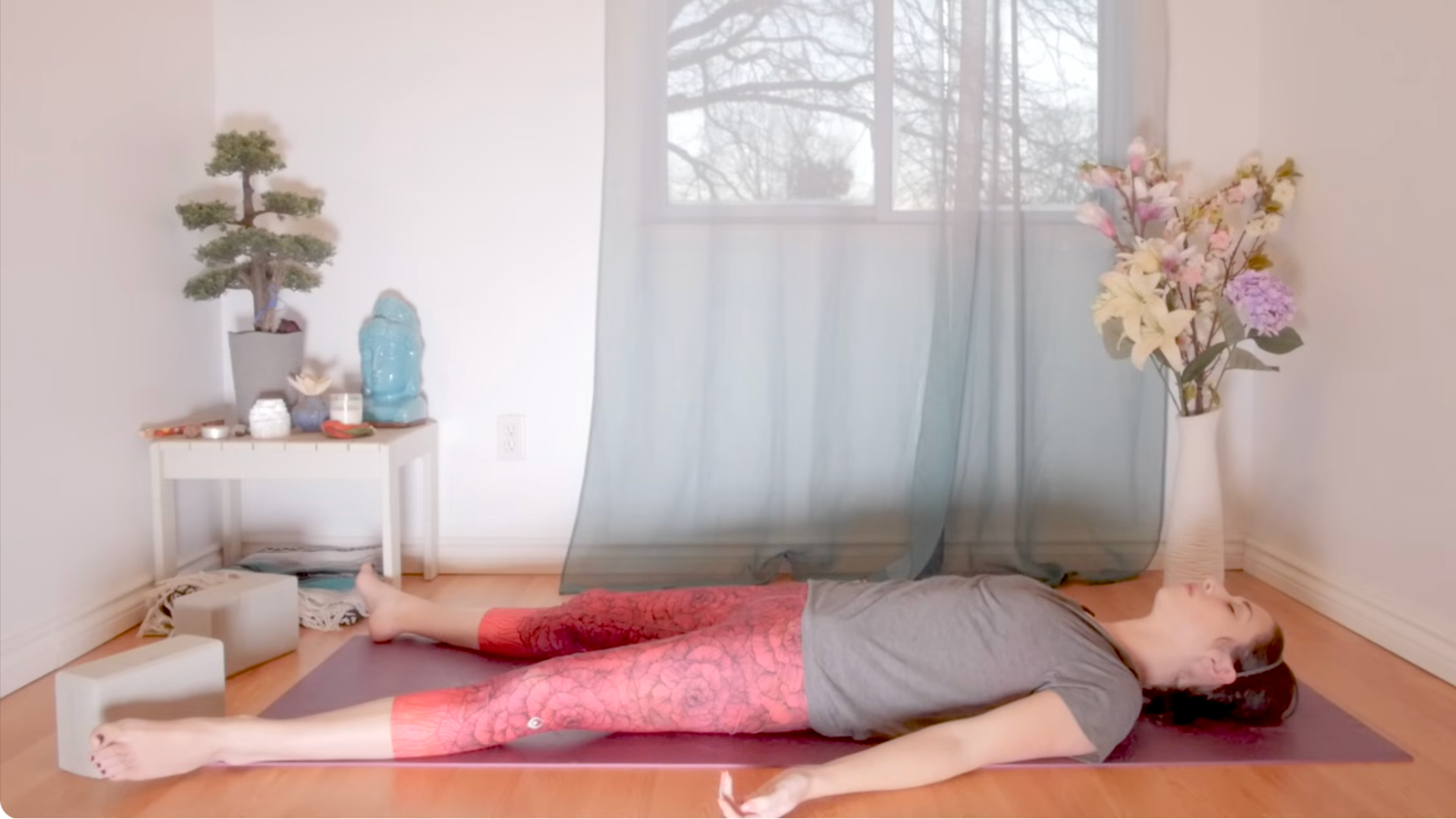 Woman lying on her mat in Savasana after practicing yoga for root chakra balancing