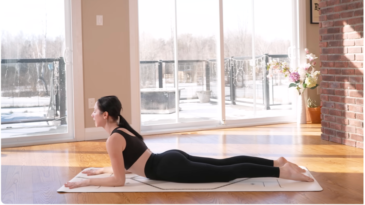 Yoga teacher on a mat practicing Sphinx Pose 
