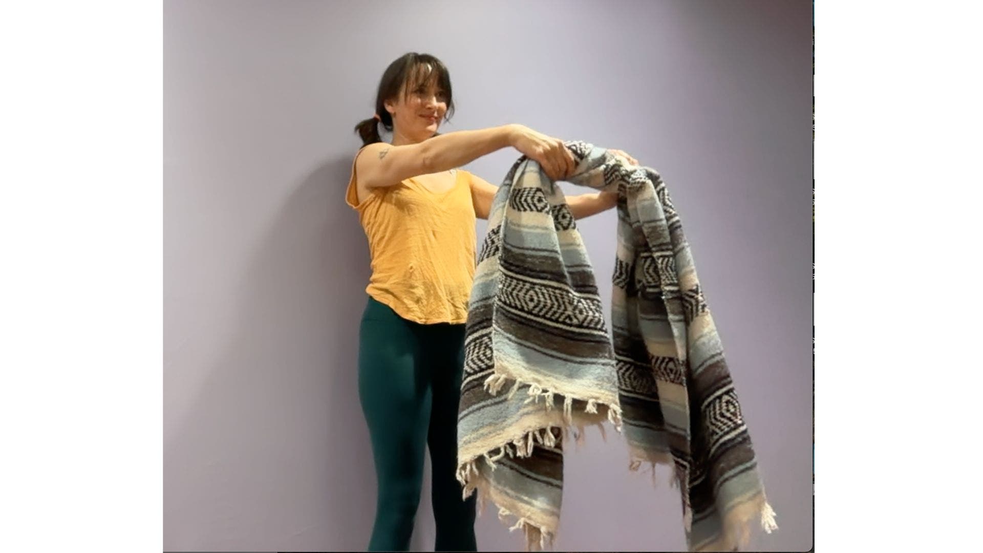 Amber Burke demonstrating wringing out yoga blankets stretch.