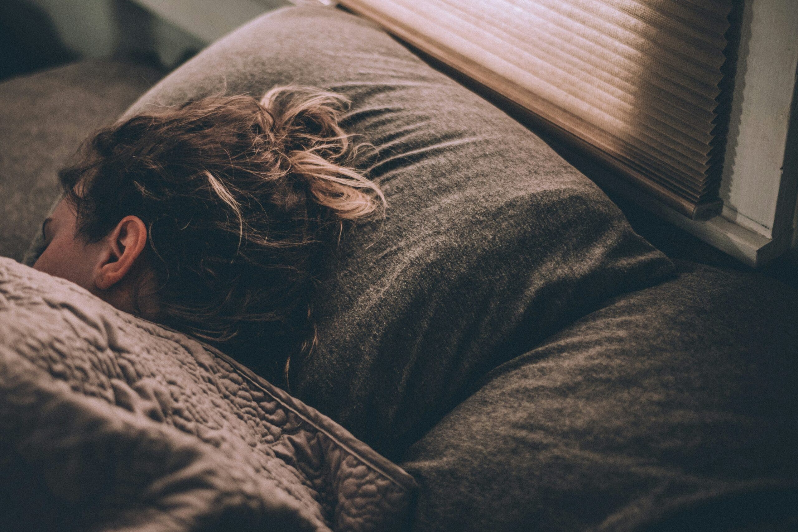 Woman sleeping in bed under covers.