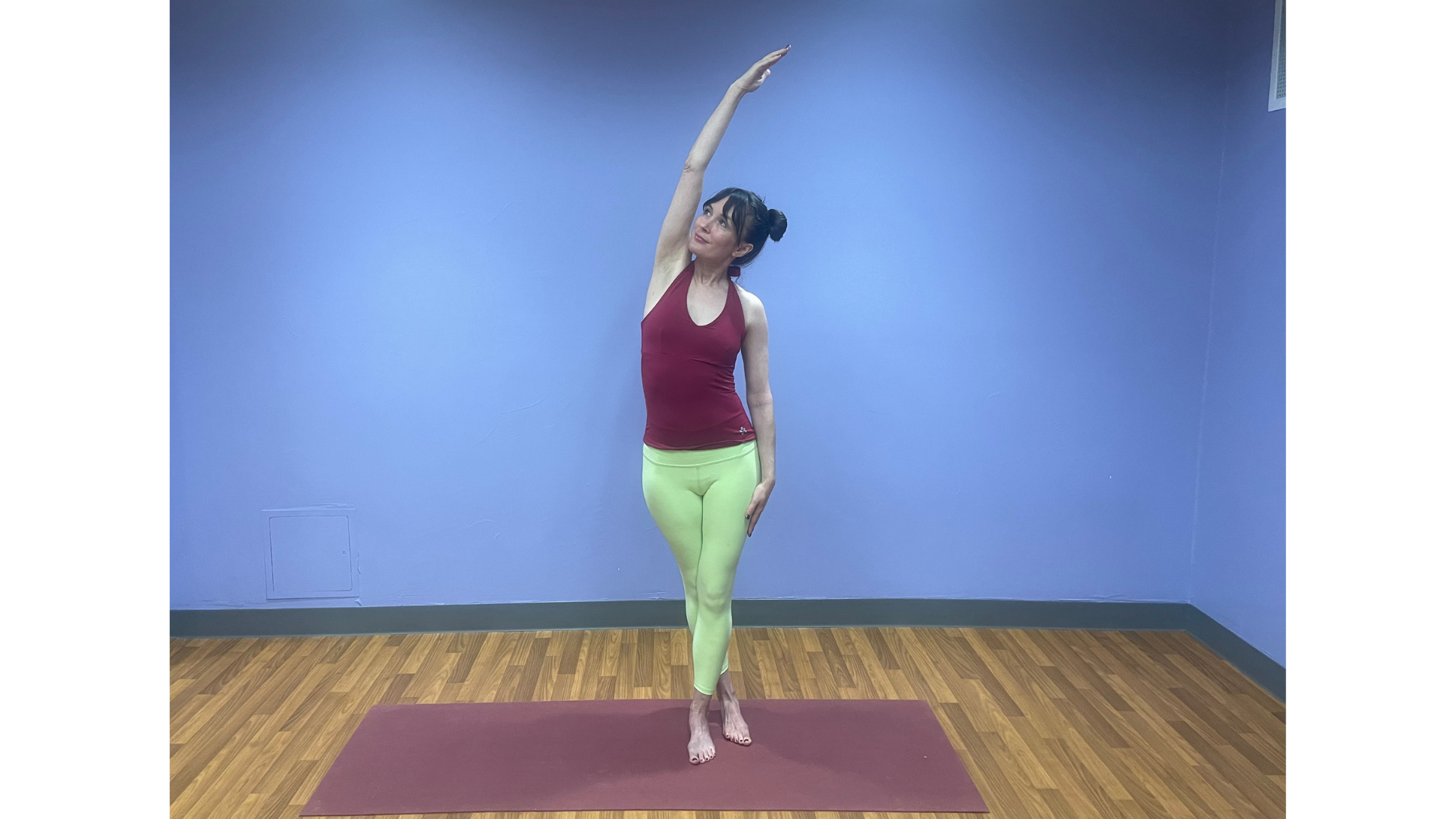 Woman standing on a yoga mat practicing an after-weight-lifting stretch