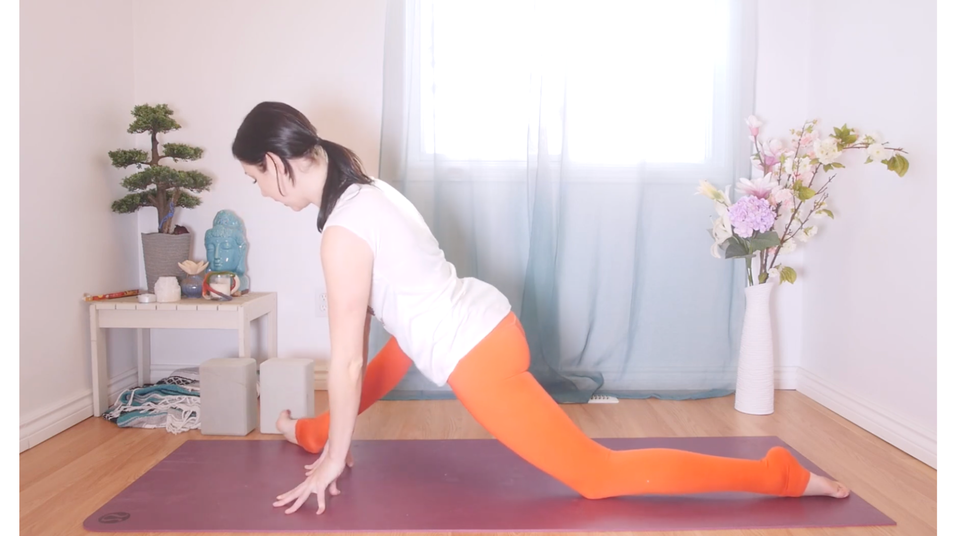 Woman kneeling on a yoga mat in low lunge with her front knee leaning to the side