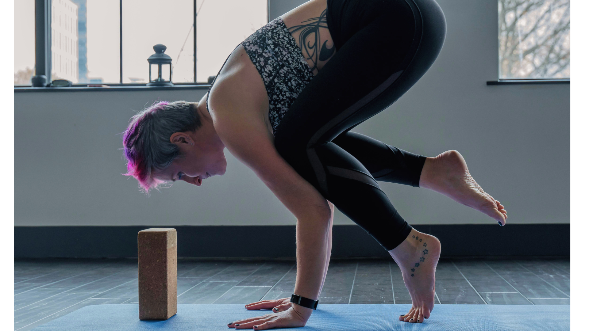 Woman on a yoga mat leaning forward onto a block