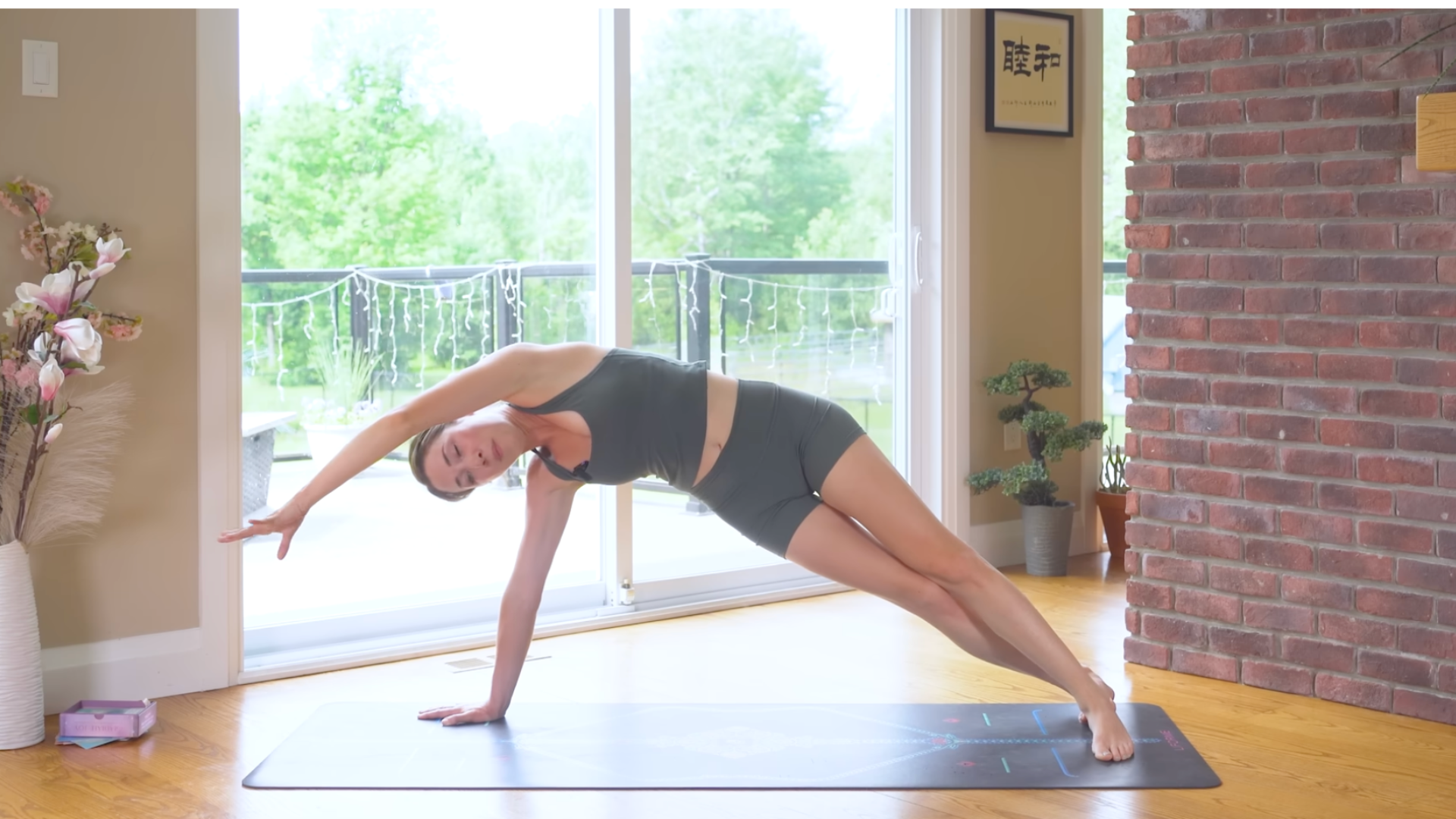 Woman with her right hand on the yoga mat and her hips lifted and her left arm reaching overhead