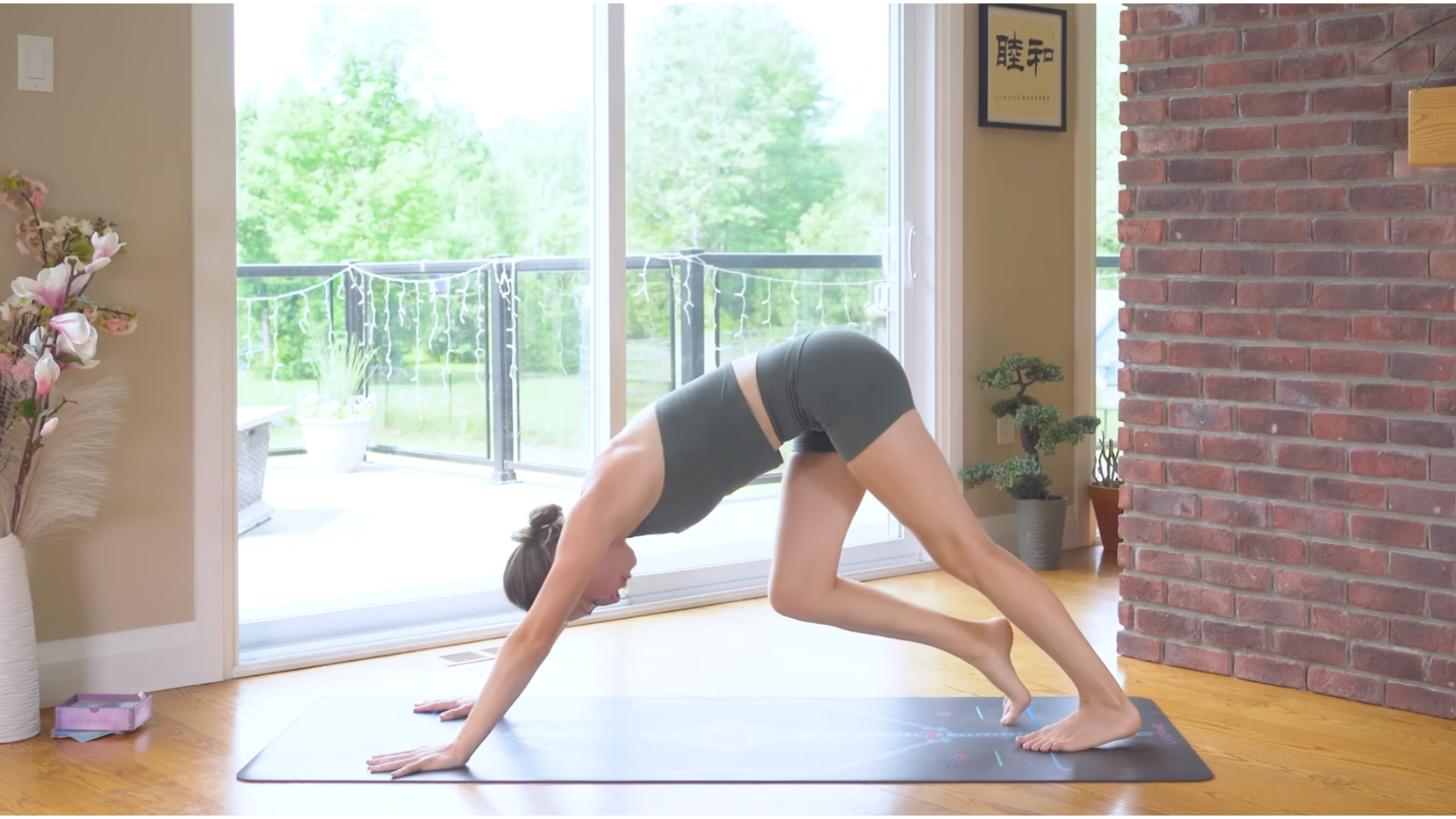 Woman in Downward-Facing Dog on a yoga mat with one knee bent and one leg straight