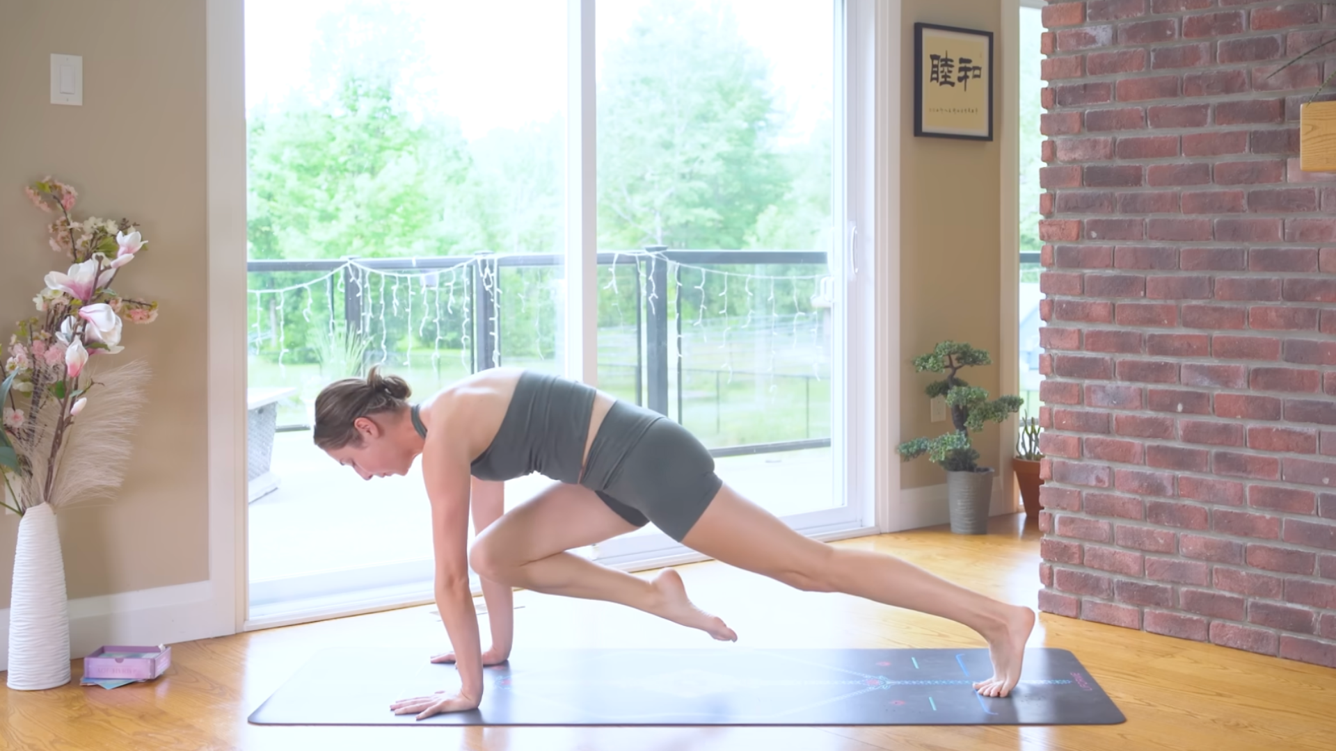 Woman on a yoga mat practicing drawing her knee toward her nose from Plank Pose