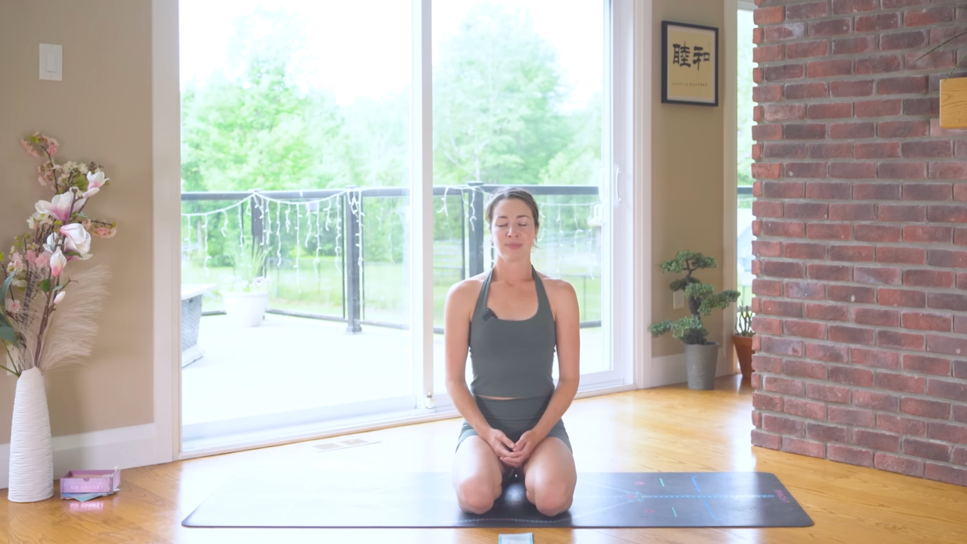Woman kneeling on a yoga mat with her eyes shut following a 10-minute yoga and pilates core-strengthening routine