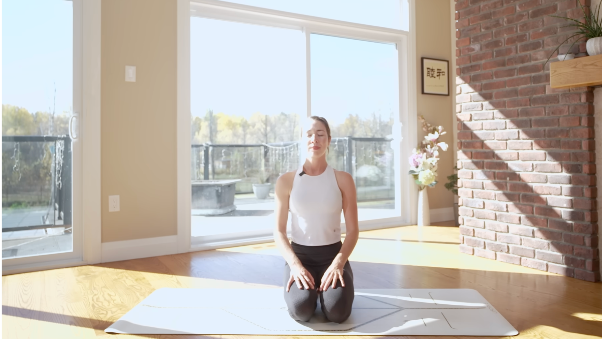 Yoga teacher kneeling on a mat pausing in meditation