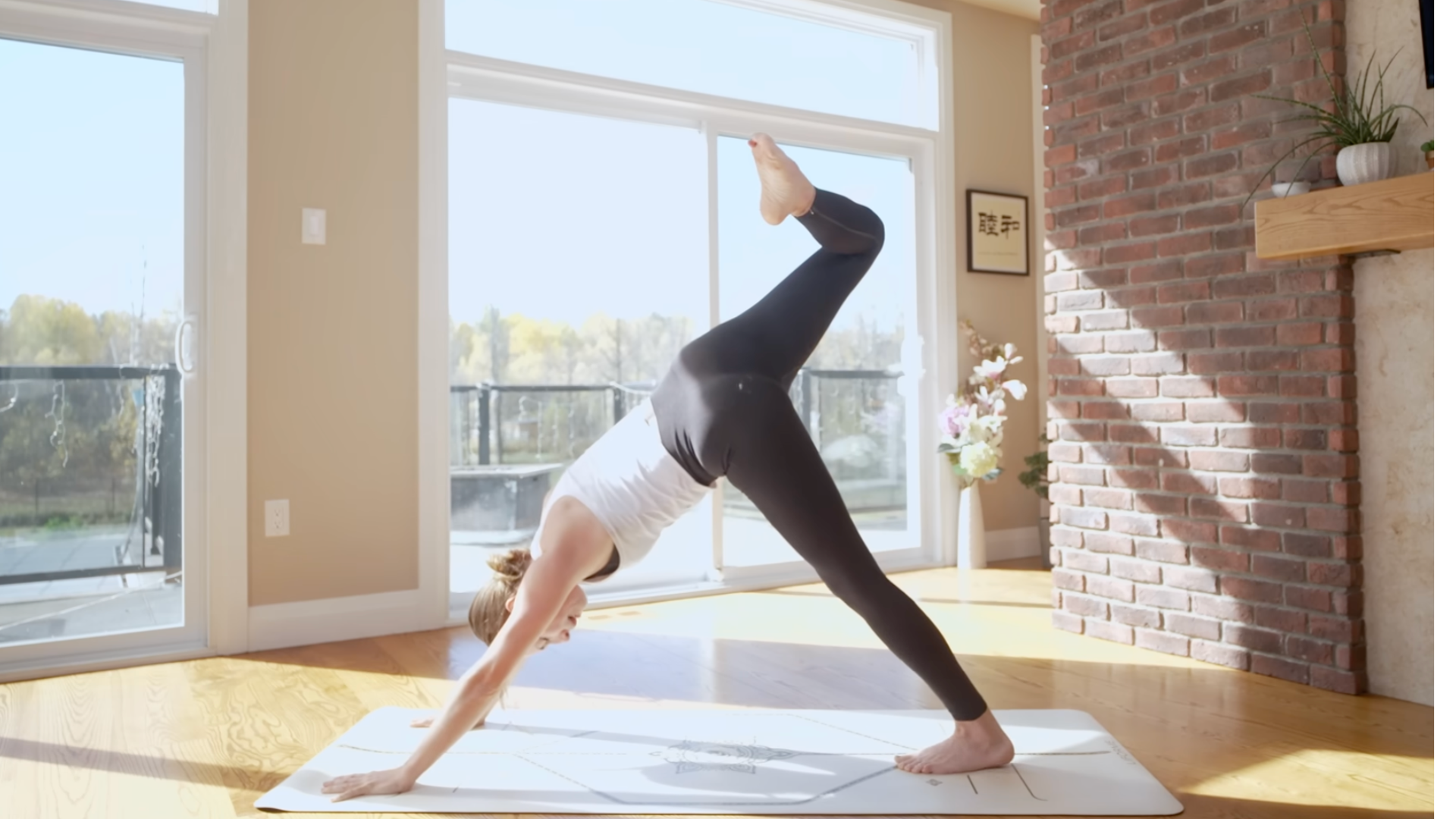 Woman on a yoga mat during a 10-minute yoga practice with her right leg lifted behind her in three-legged dog
