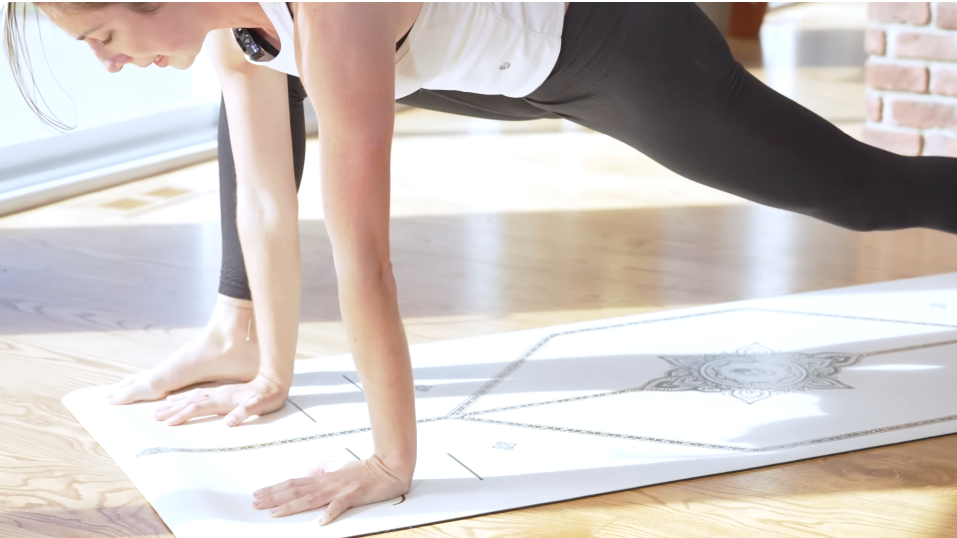 Yoga teacher on a yoga mat with her hands at the front of the mat in a low lunge known as Lizard Pose
