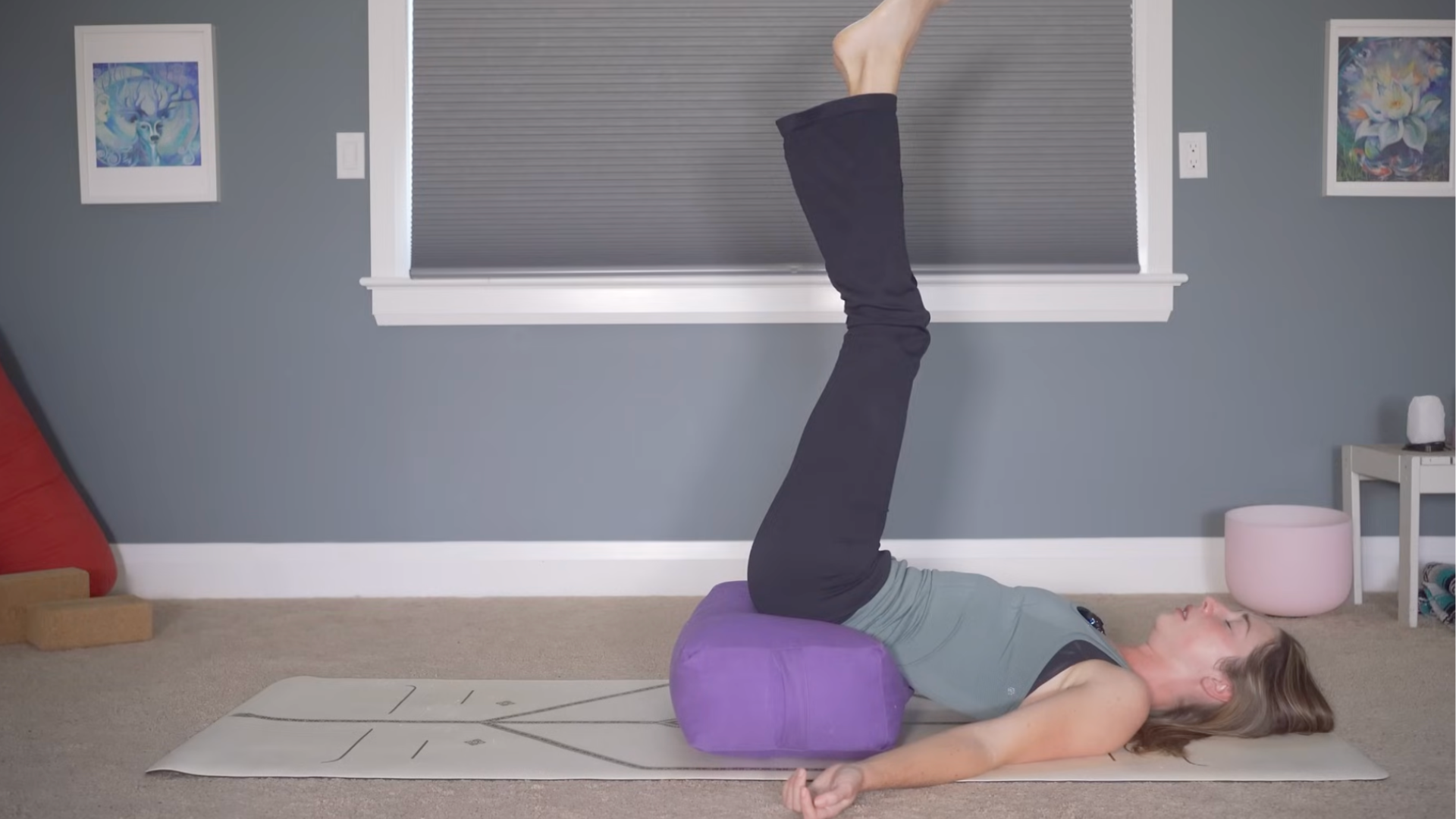 Woman with a bolster underneath her hips and her legs reaching toward the sky