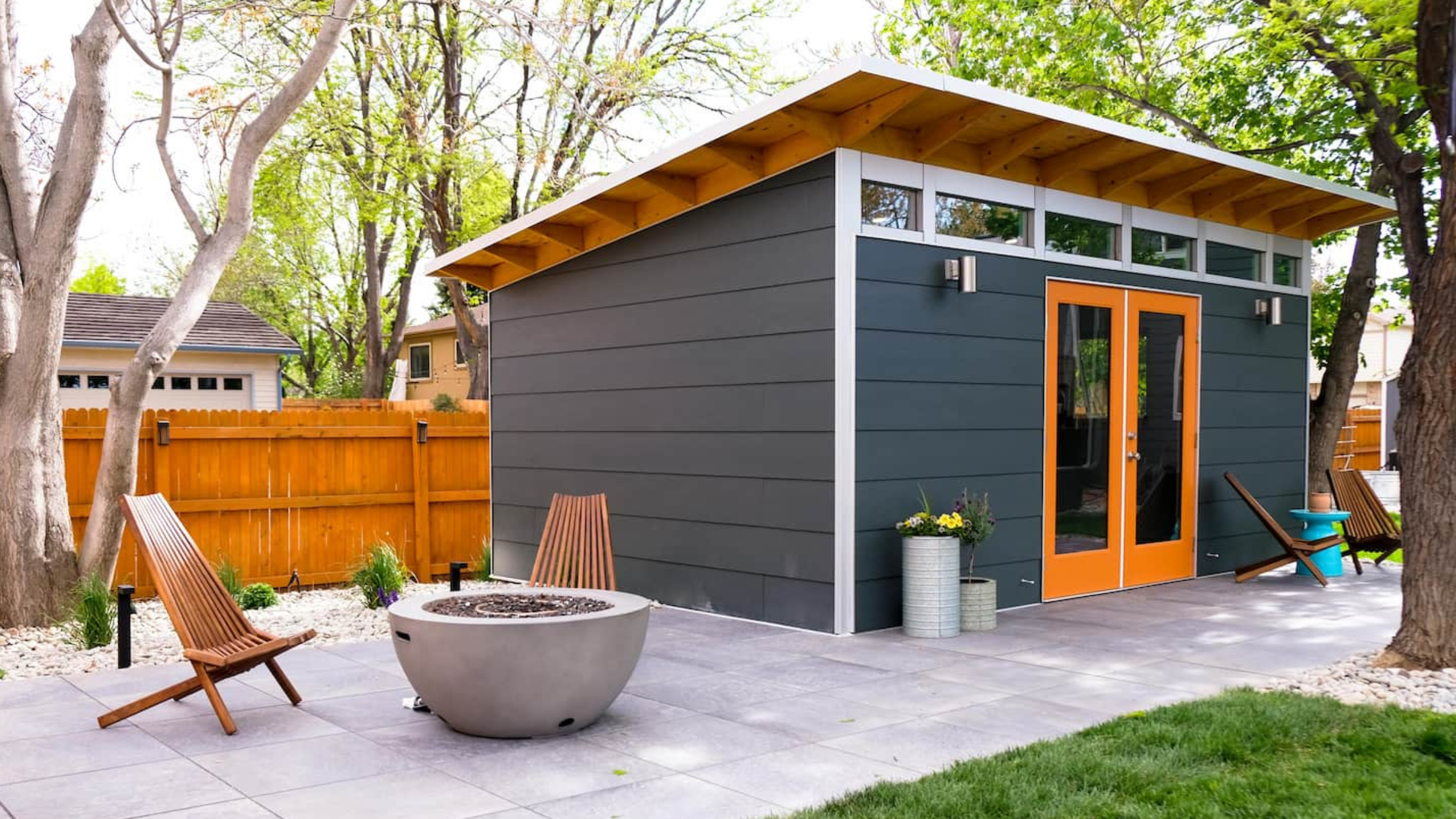 gray shed outside with patio area and orange trim under trees, best yoga gifts