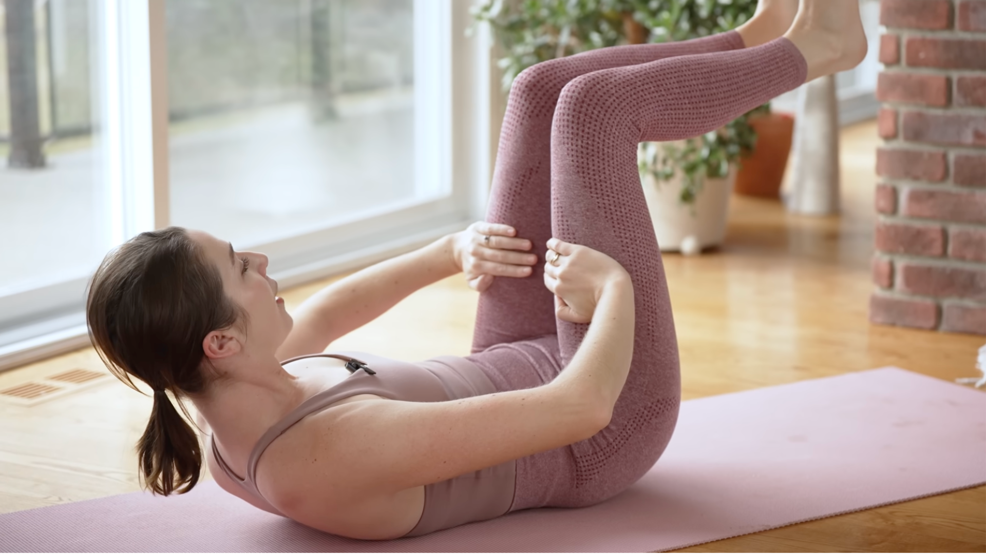 Woman lying on a mat lifting her head and knees