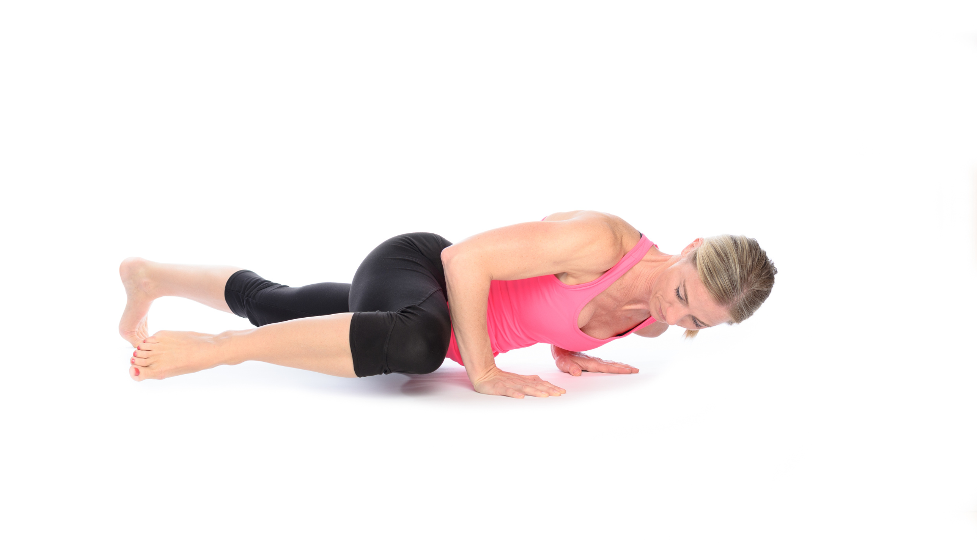Woman practicing a spider man push-up by drawing her right knee toward her right elbow