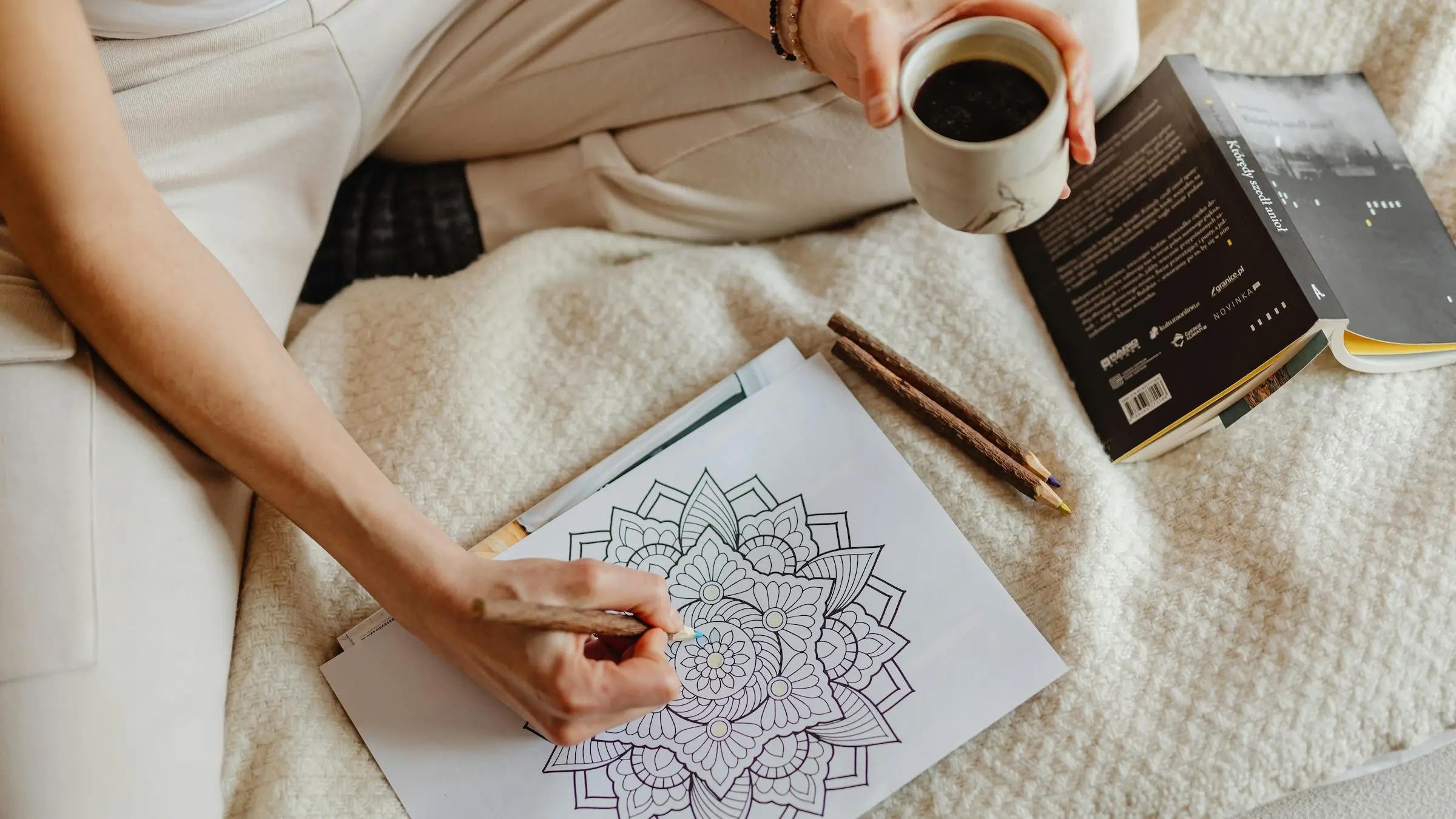 A woman coloring while drinking coffee, a mindfulness practice known as habit stacking