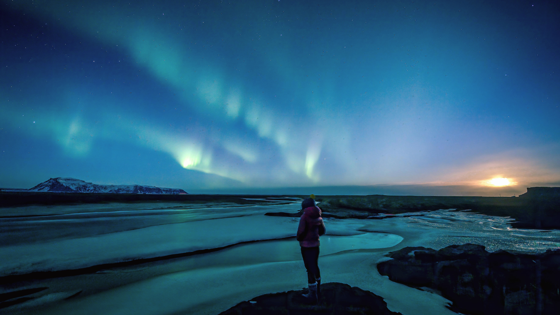Woman standing beneath the northern lights on winter solstice contemlating weekly horoscope for December 21-27, 2025