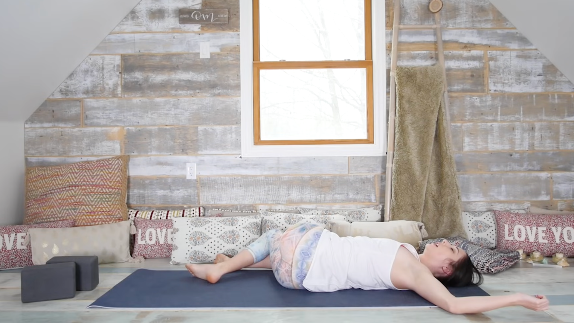 Woman lying on a yoga mat with her knees falling over to the right in a reclined twist