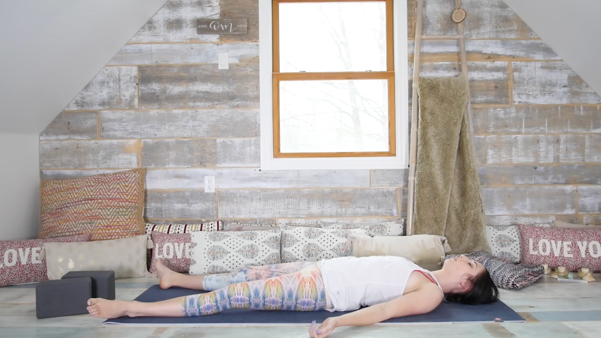 Woman lying on a yoga mat in Savasana while practicing yoga poses for the solar plexus chakra 