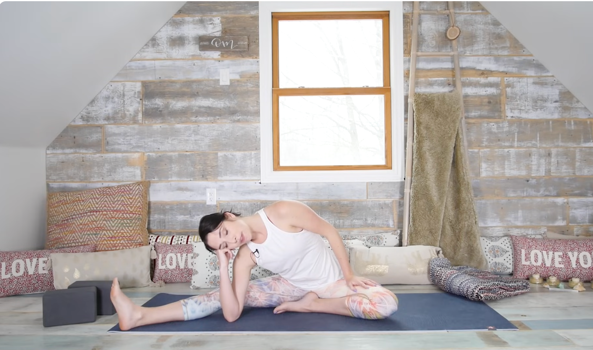 Woman sitting on a yoga mat with one leg straight and one knee bent
