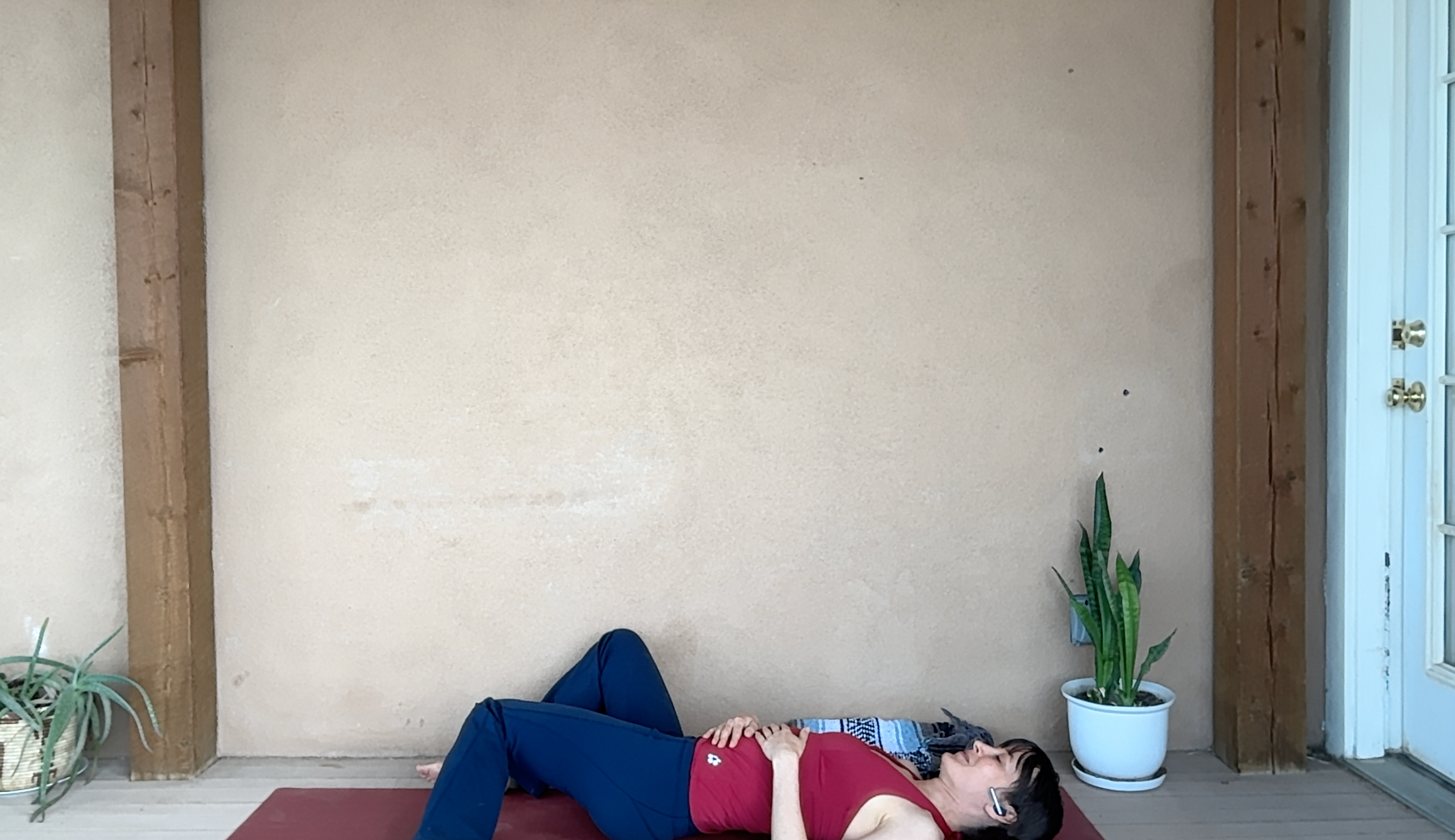Image of woman lying on yoga mat with knees bent to one side.