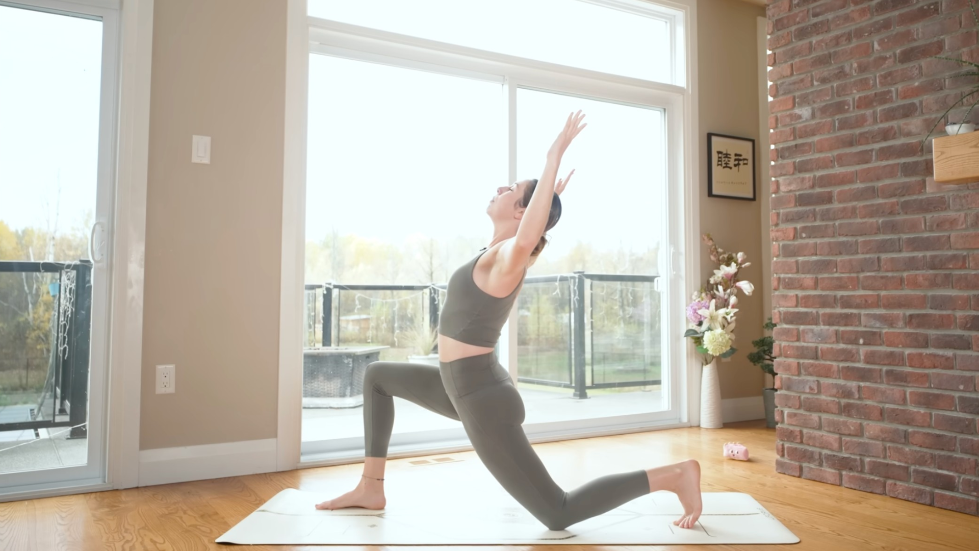 Woman in a Low Lunge with her left knee to the mat and her arms bent to create a backbend