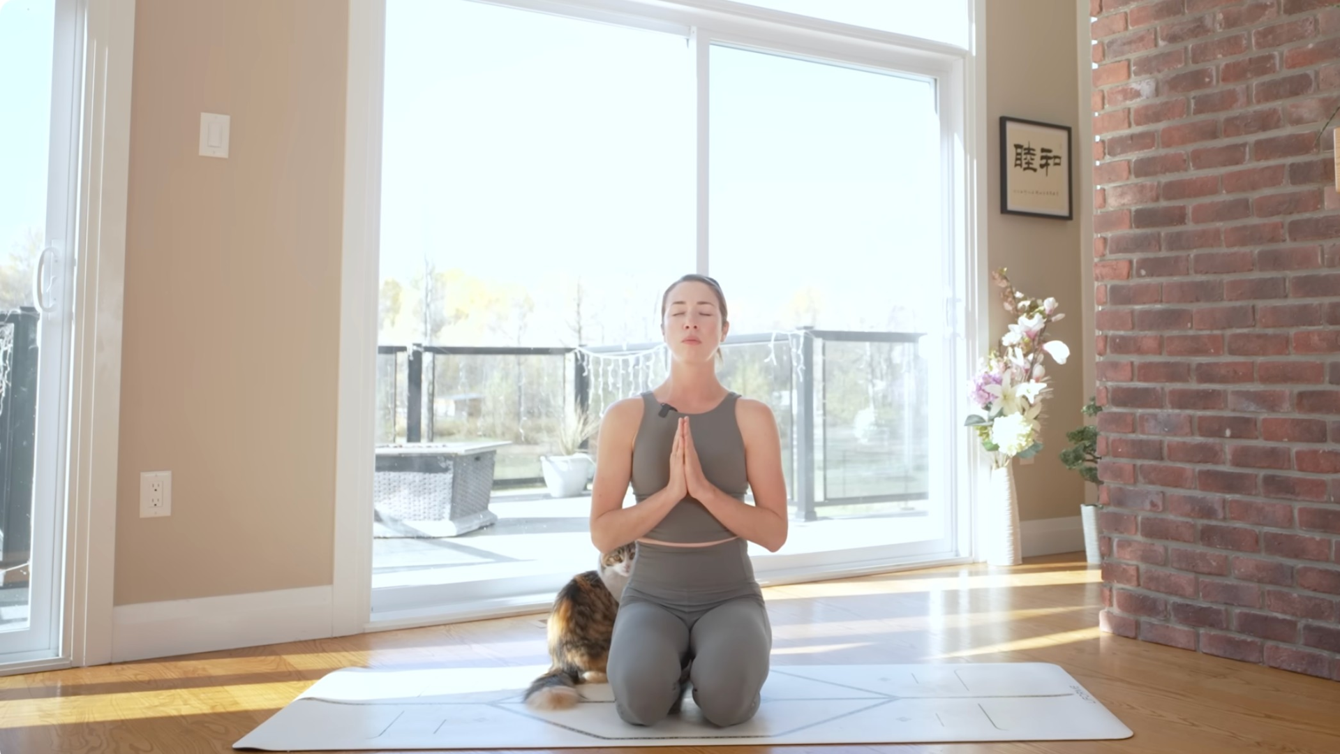 Woman sitting back on her heels after morning stretches while her cat sits alongside her