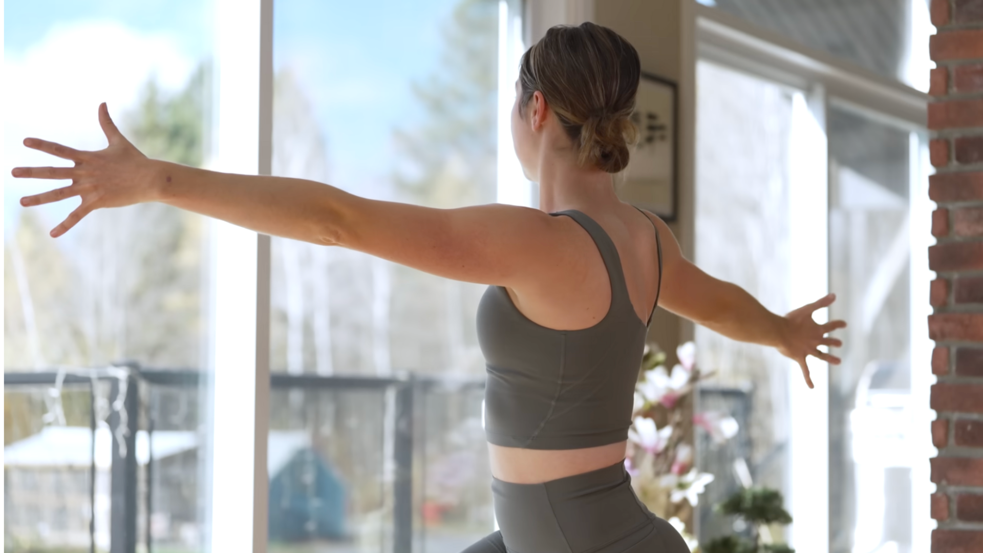 Woman practicing a high lunge twist with her arms reaching in opposite directions