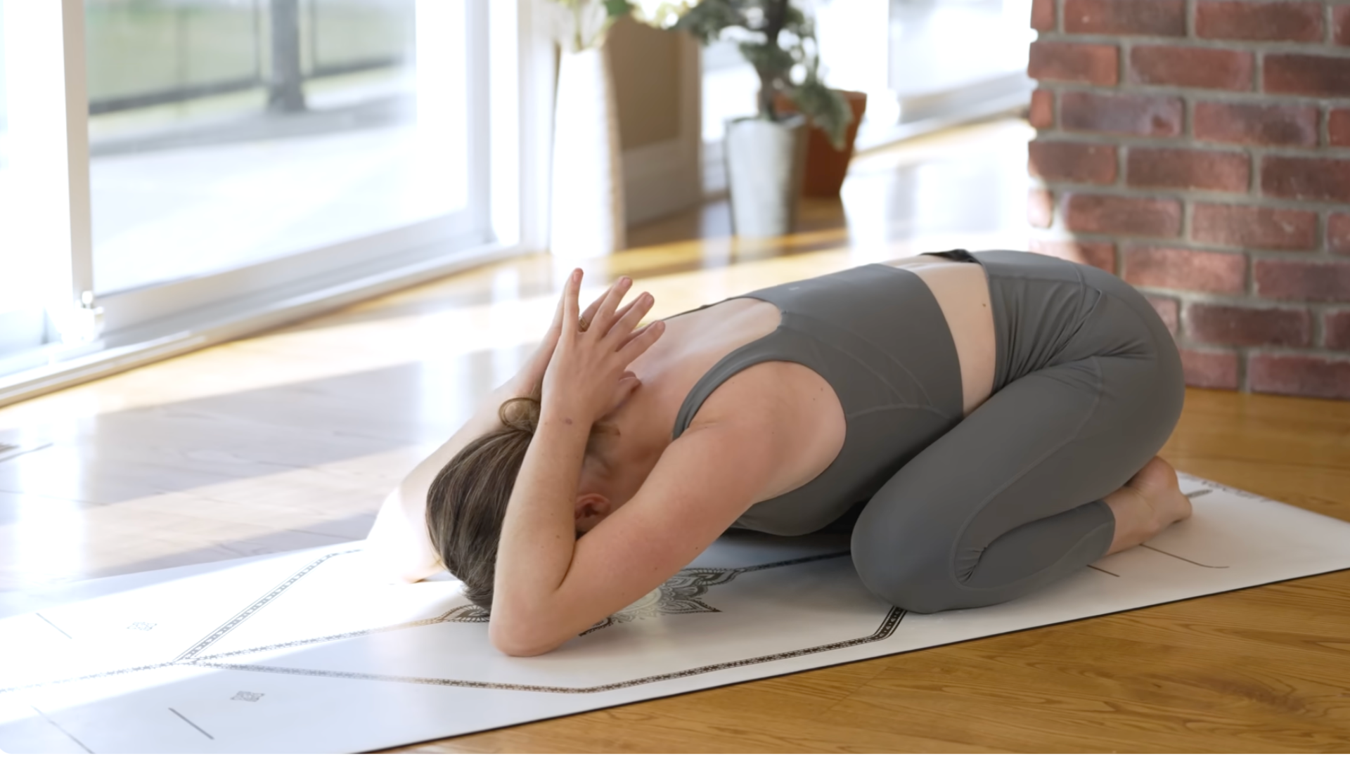 Woman kneeling on a mat during Child's Pose with her palms together