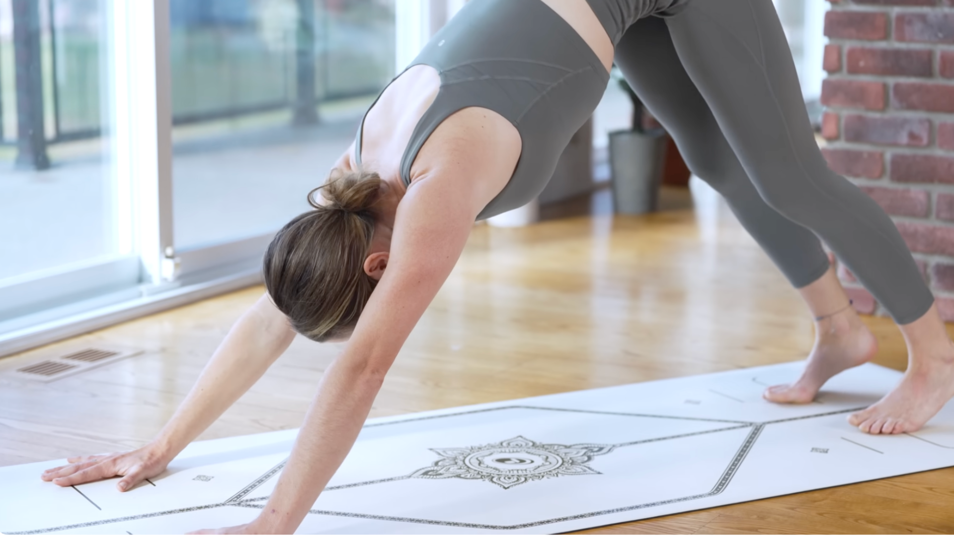 Woman on a mat in Downward-Facing Dog with her hands and feet on the mat in an inverted V