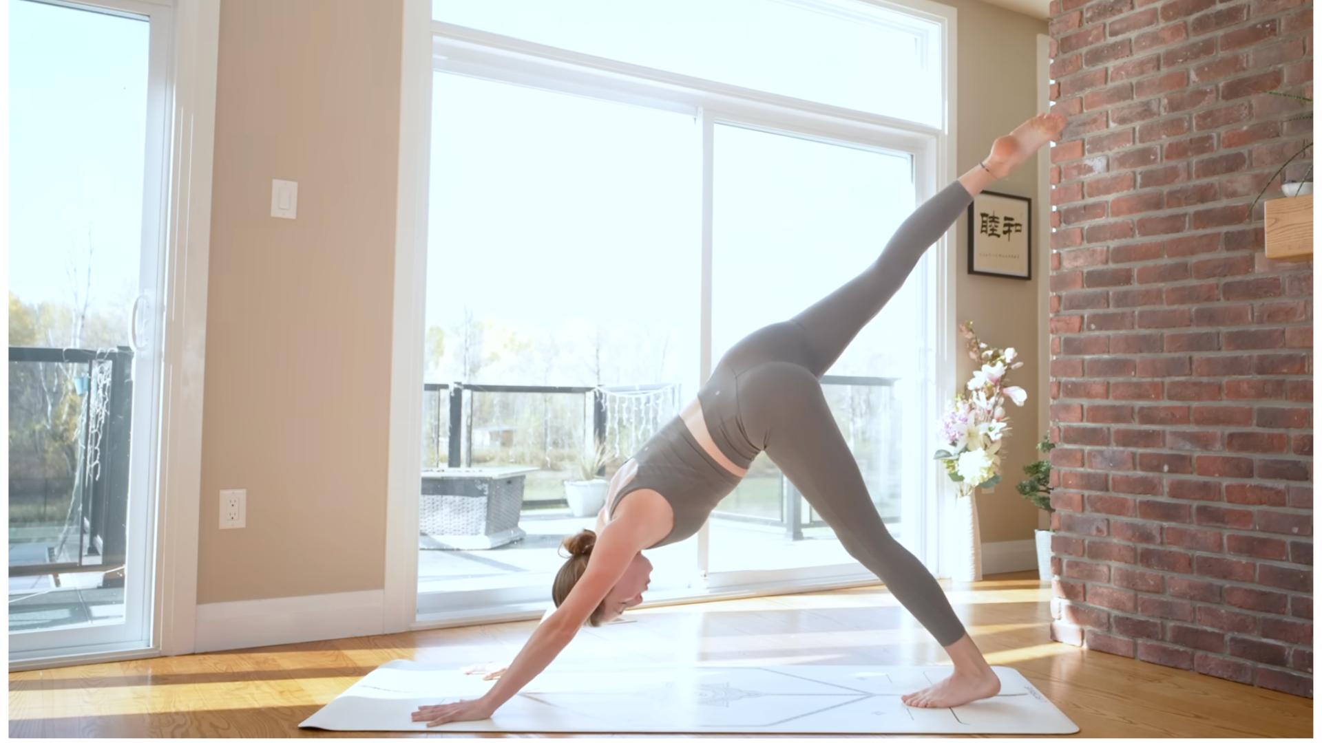 Woman on a mat in Three-Legged Dog lifting her right leg and then lowering her left heel