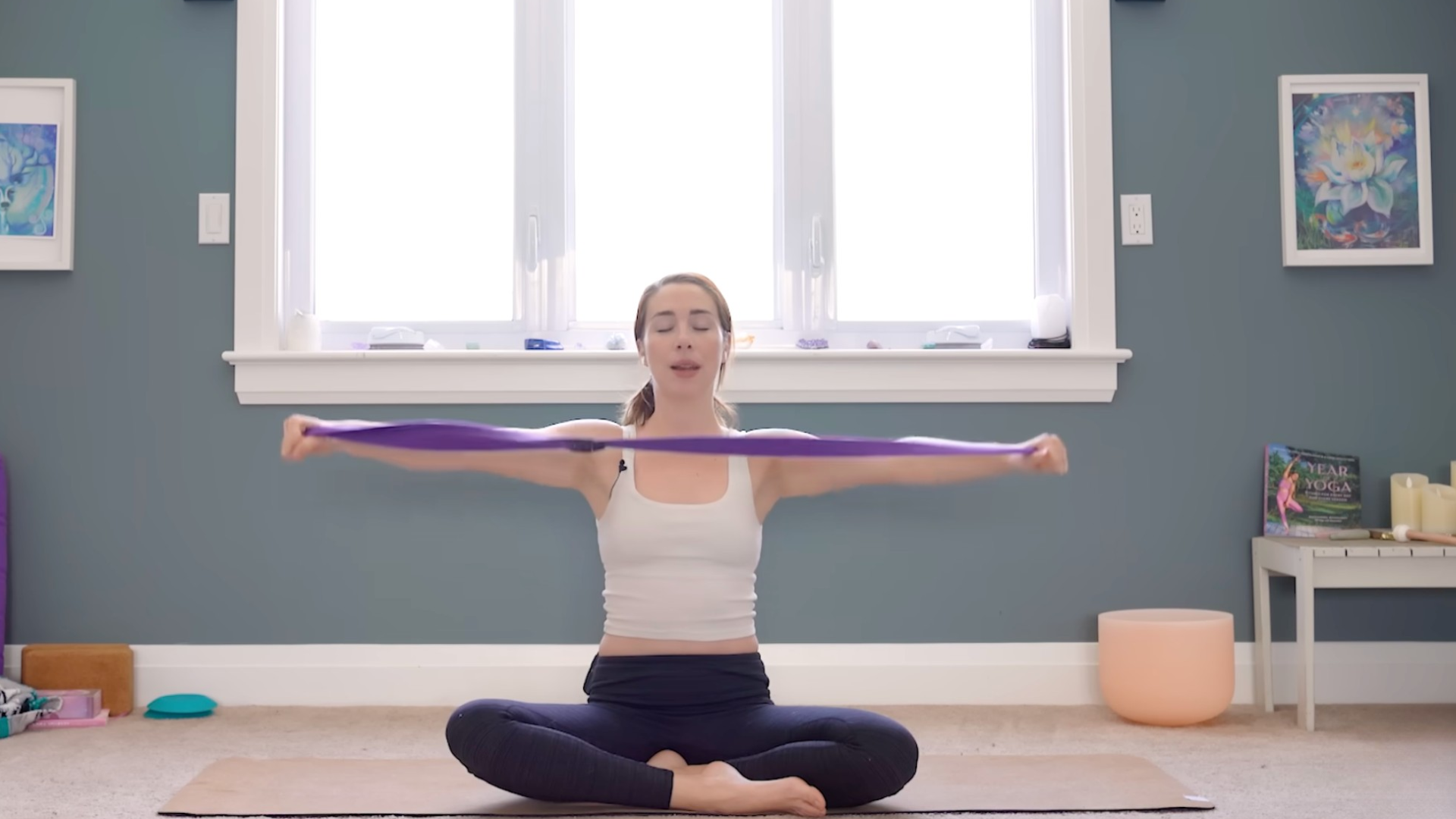 Woman sitting cross-legged holding a strap between her hands