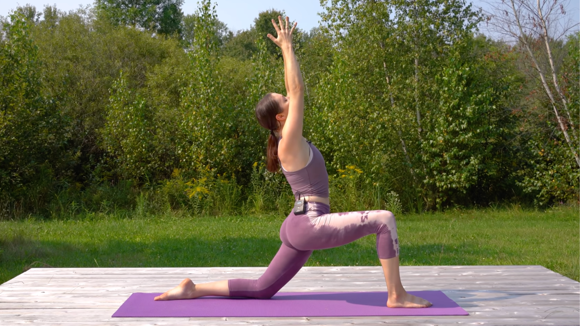 Yoga teacher in a Low Lunge with her arms reaching alongside her head