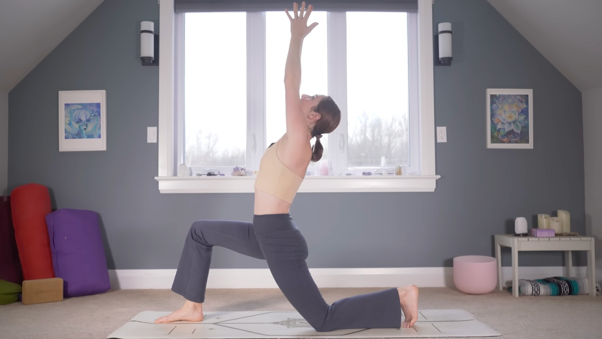 Woman kneeling on a yoga mat lifting her arms in Low Lunge