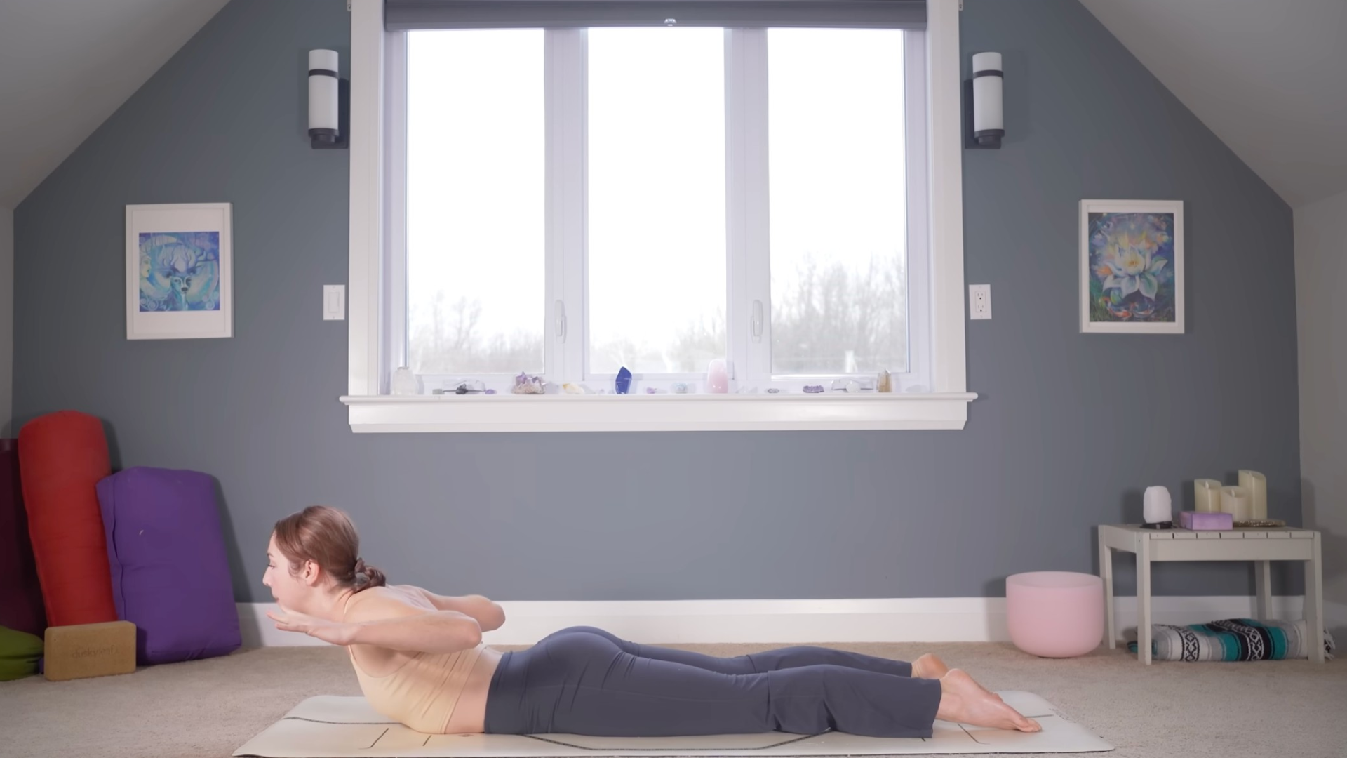 Woman lying on belly on a mat lifting chest and hands off the mat