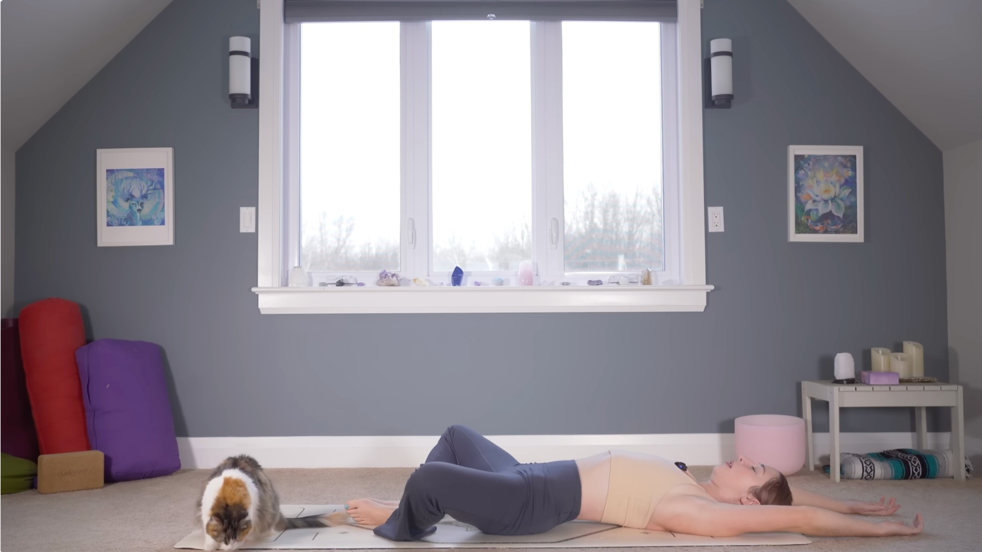 Woman lying on a mat practicing Reclined Bound Angle Pose with her feet together and arms alongside her ears