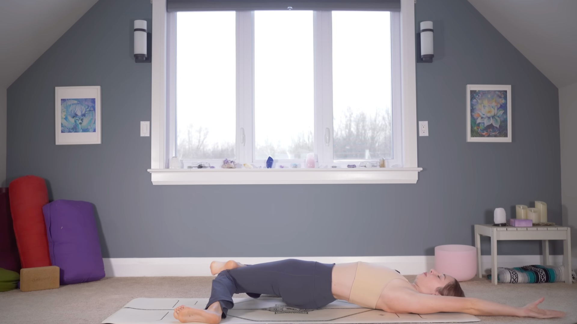 Woman lying on a yoga mat with her knees bent and leaning over to her right side in Reclining Windshield Wipers