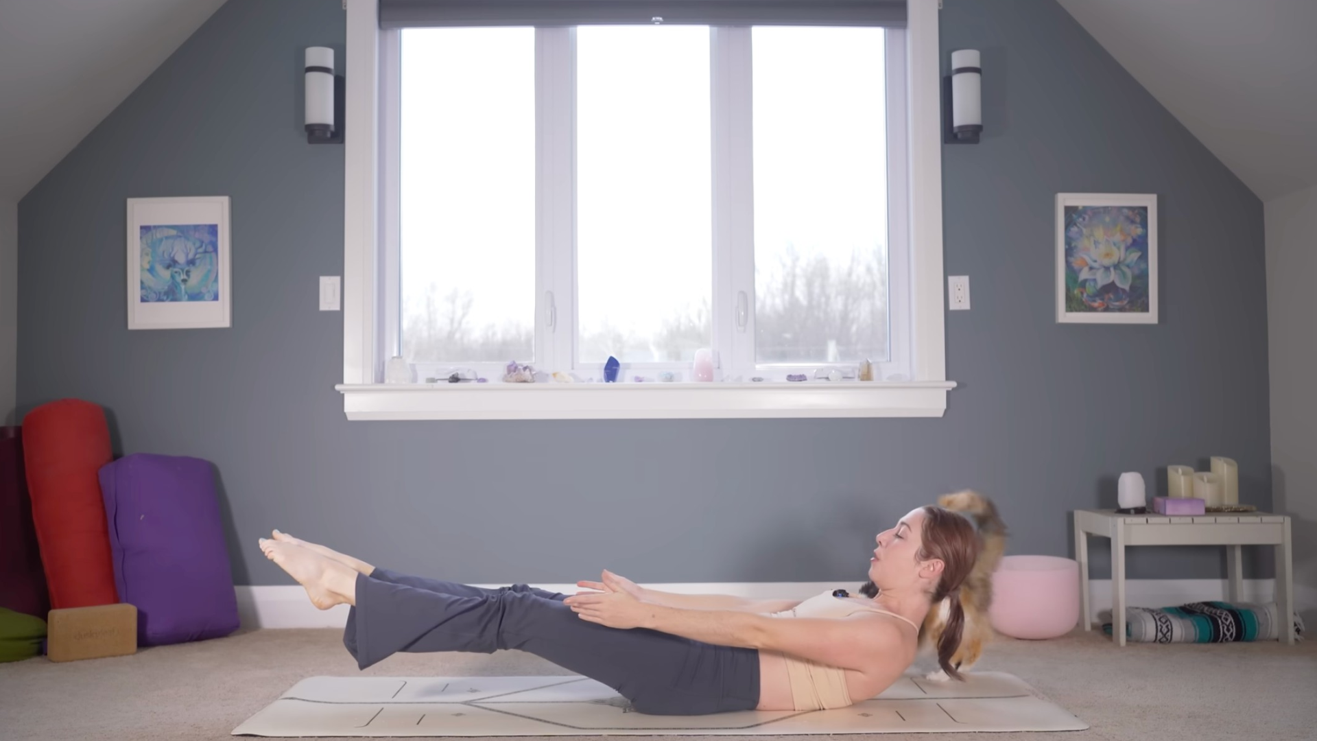 Woman reclining on a yoga mat lifting her head and legs in a Low Boat Pose
